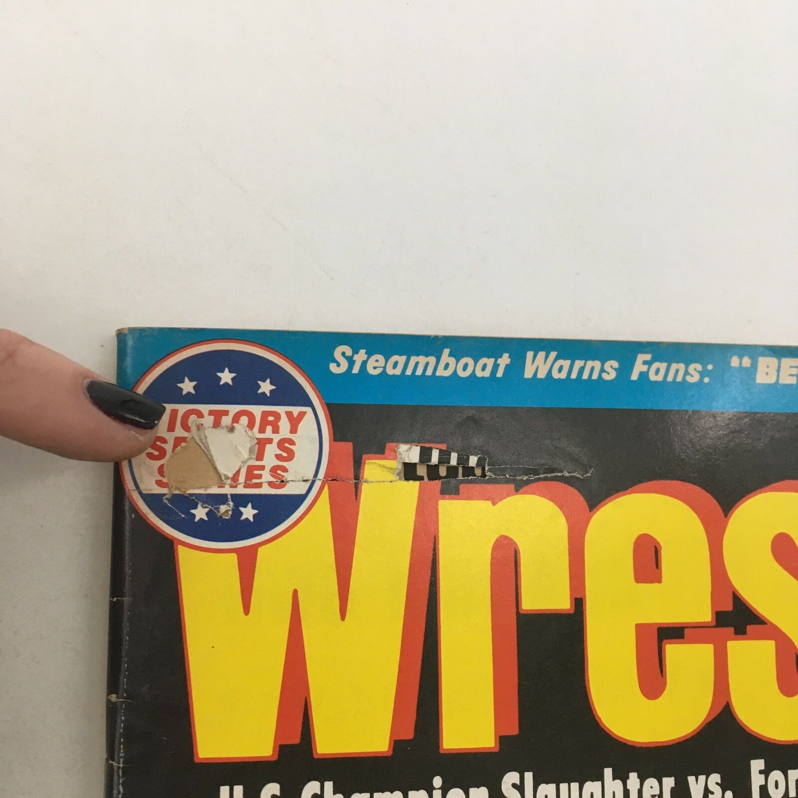 Close-up of the top section of The Wrestler Magazine March 1982 cover, indicating wear with a torn Victory Sports Series sticker and highlighting the featured wrestlers.