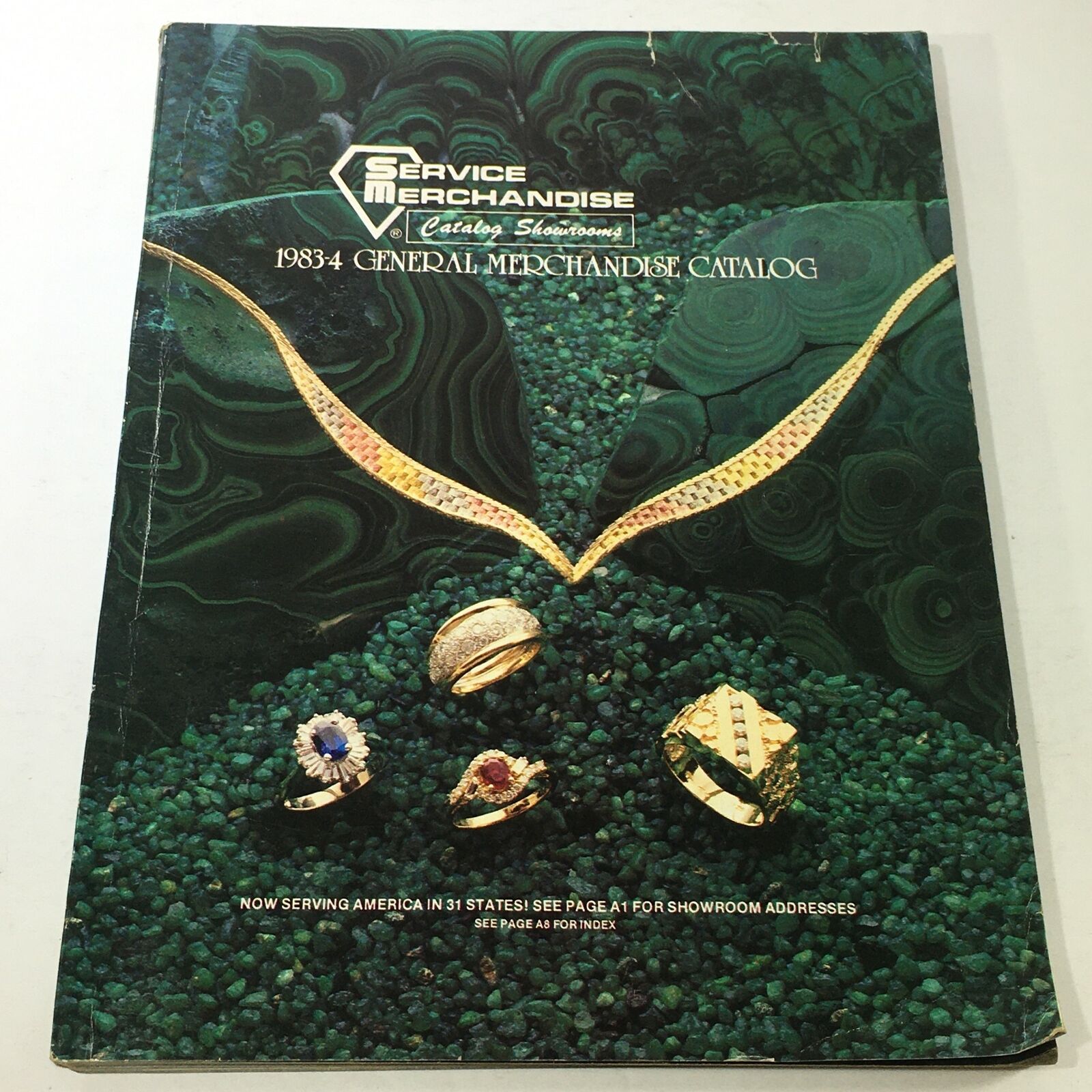 Cover of the VTG Service Merchandise Catalog Showroom 1983-1984 Volume 14 featuring jewelry designs, including rings and necklaces, set against a green stone background, highlighting vintage merchandise.