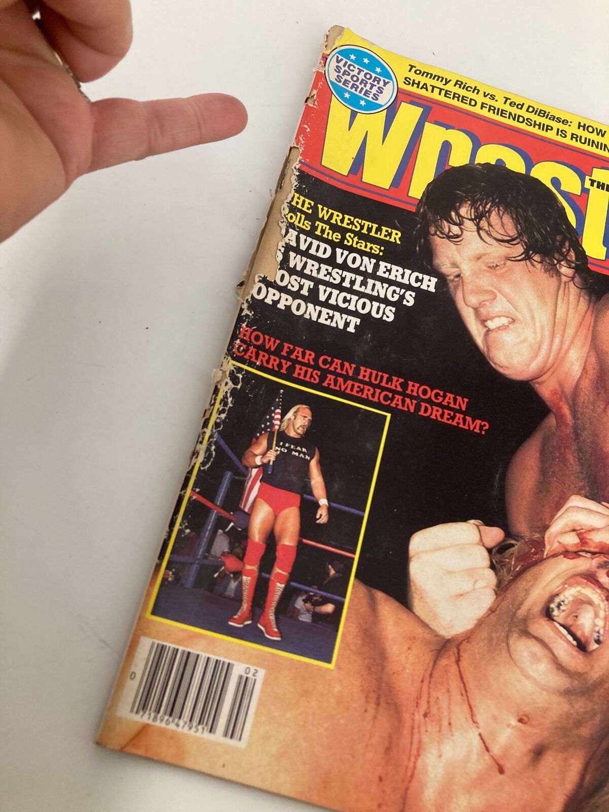 Close-up of the cover of VTG The Wrestler Magazine from February 1984, showcasing the wrestling action featuring Hulk Hogan and David Von Erich. The magazine displays wear indicative of its vintage status, enhancing its collectible appeal.