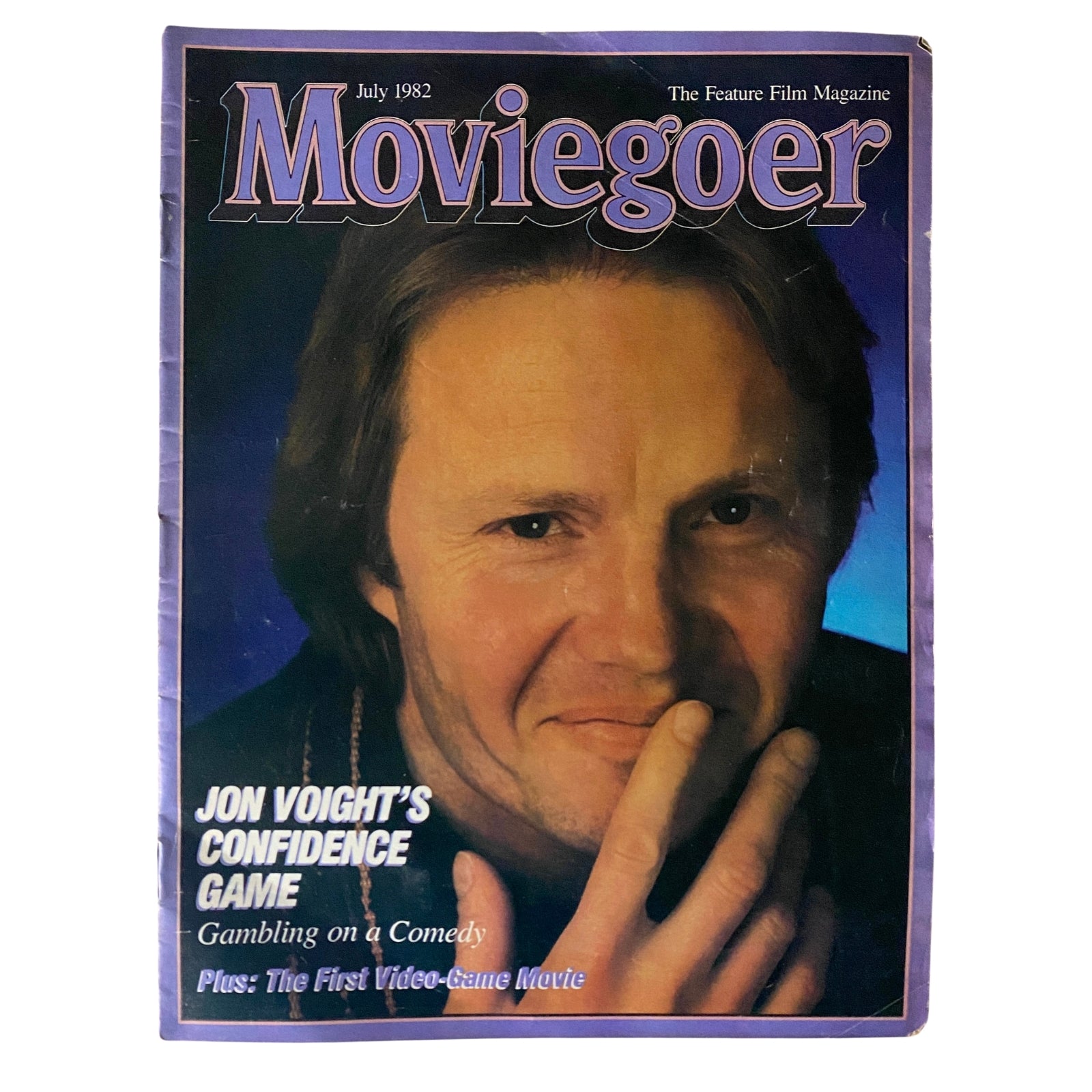 Cover of Moviegoer Magazine from July 1982 featuring Jon Voight, titled 'Jon Voight's Confidence Game'. The magazine discusses various films including the first video-game movie and highlights Voight's comedic role, capturing the essence of early 80s cinema.
