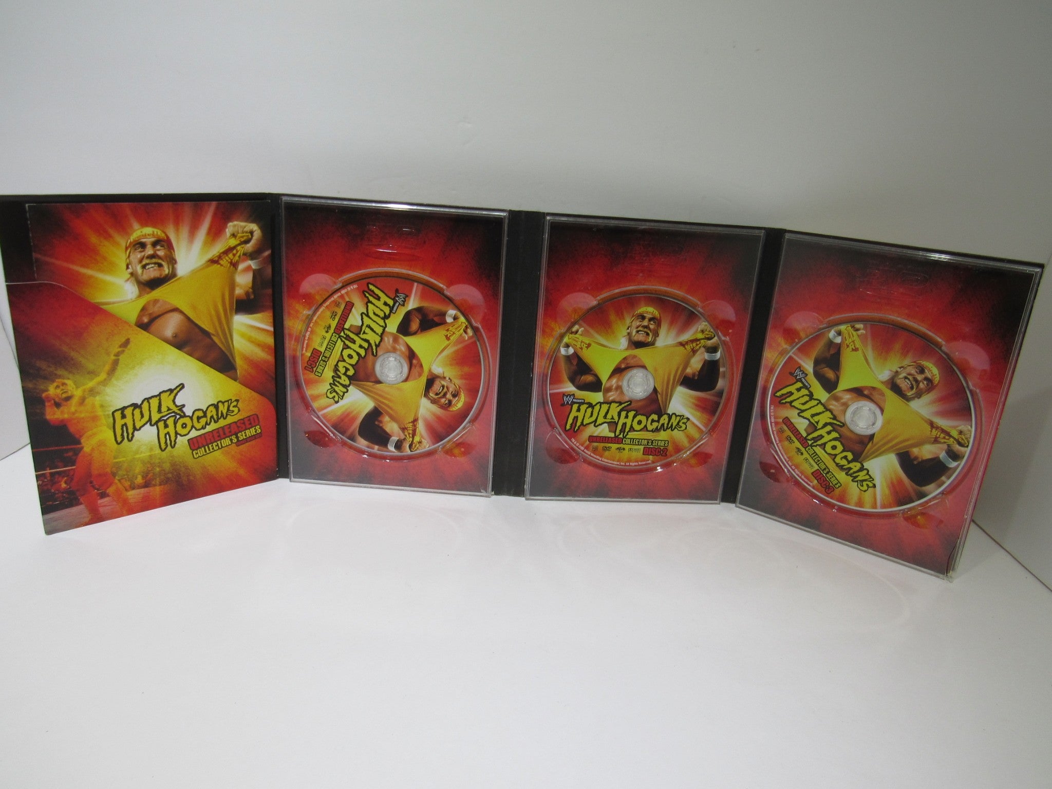 Interior view of Hulk Hogan's Unreleased Collector's Series (2009) DVD, showcasing three discs with vibrant cover art featuring Hulk Hogan.