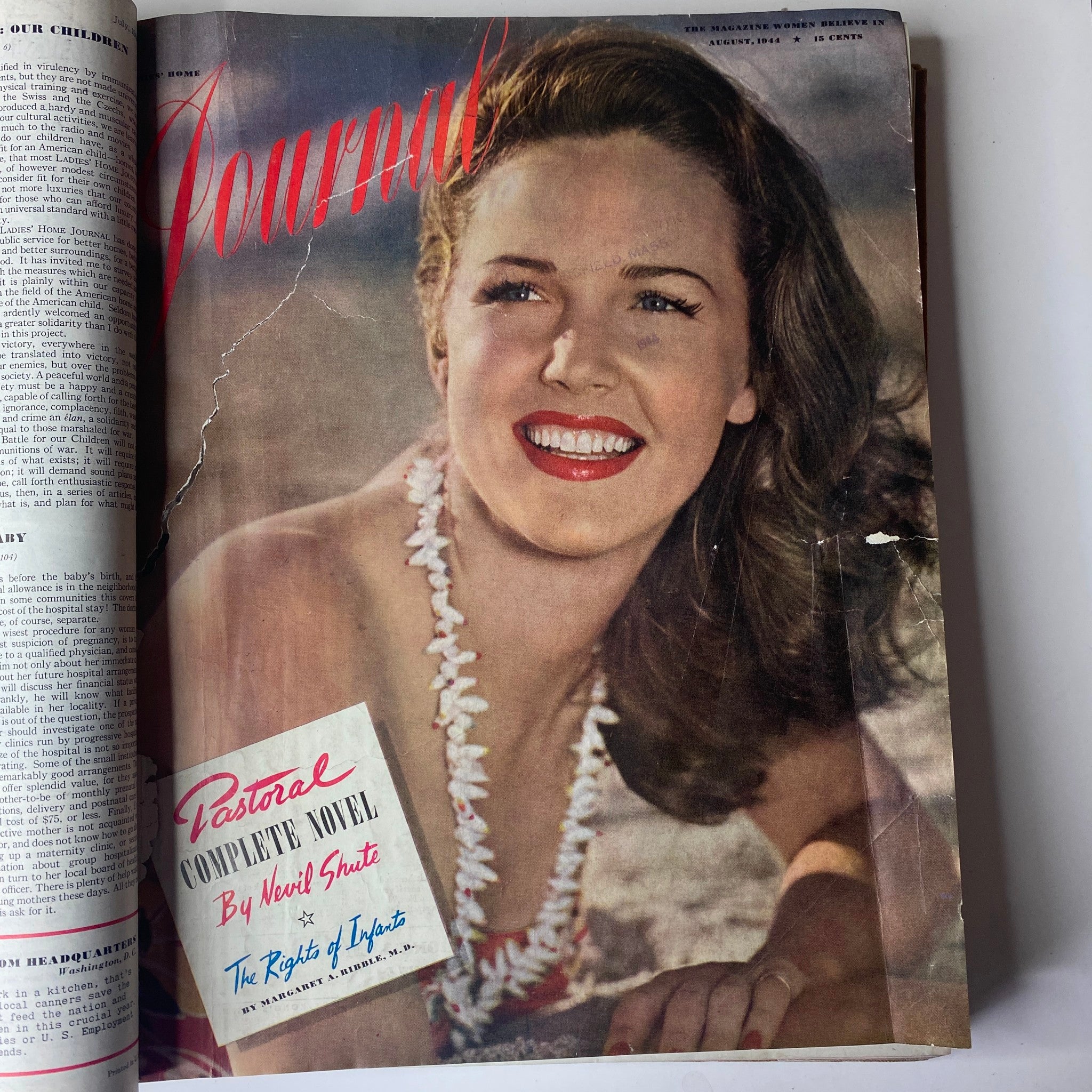 Cover of the Ladies' Home Journal, July 1944 - December 1944 featuring a smiling woman with long hair, wearing a lei, showcasing vintage American fashion from the 1940s.
