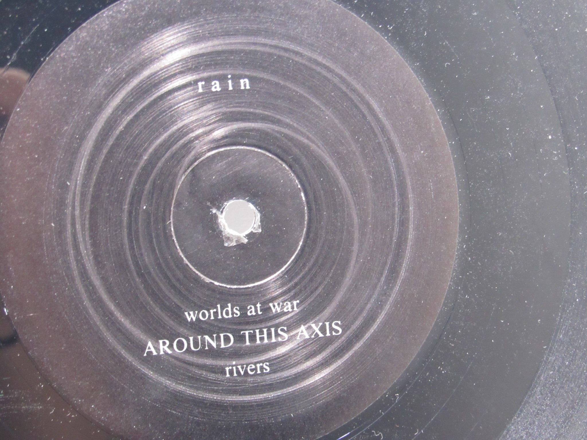 Close-up of vinyl record label for 'Rain La Vache Qui Rit Peterbilt Records Peterbilt 3 1990 Rock LP Grade: VG', featuring song titles 'worlds at war' and 'rivers'.