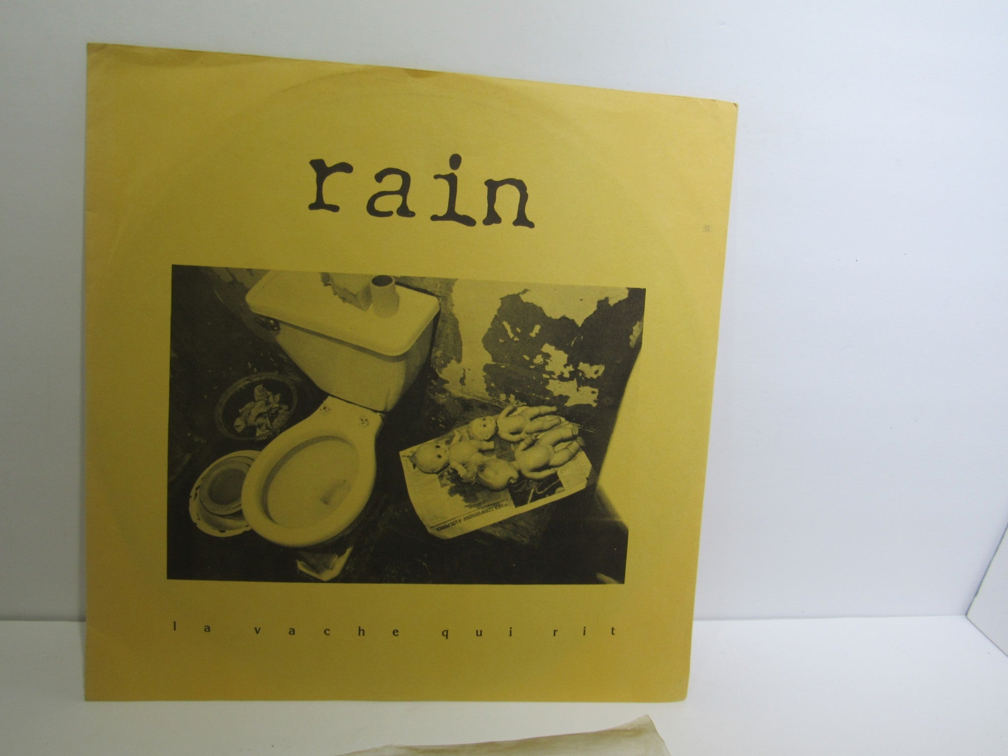 Cover of 'Rain La Vache Qui Rit Peterbilt Records Peterbilt 3 1990 Rock LP Grade: VG', featuring a striking image of a toilet among various objects.
