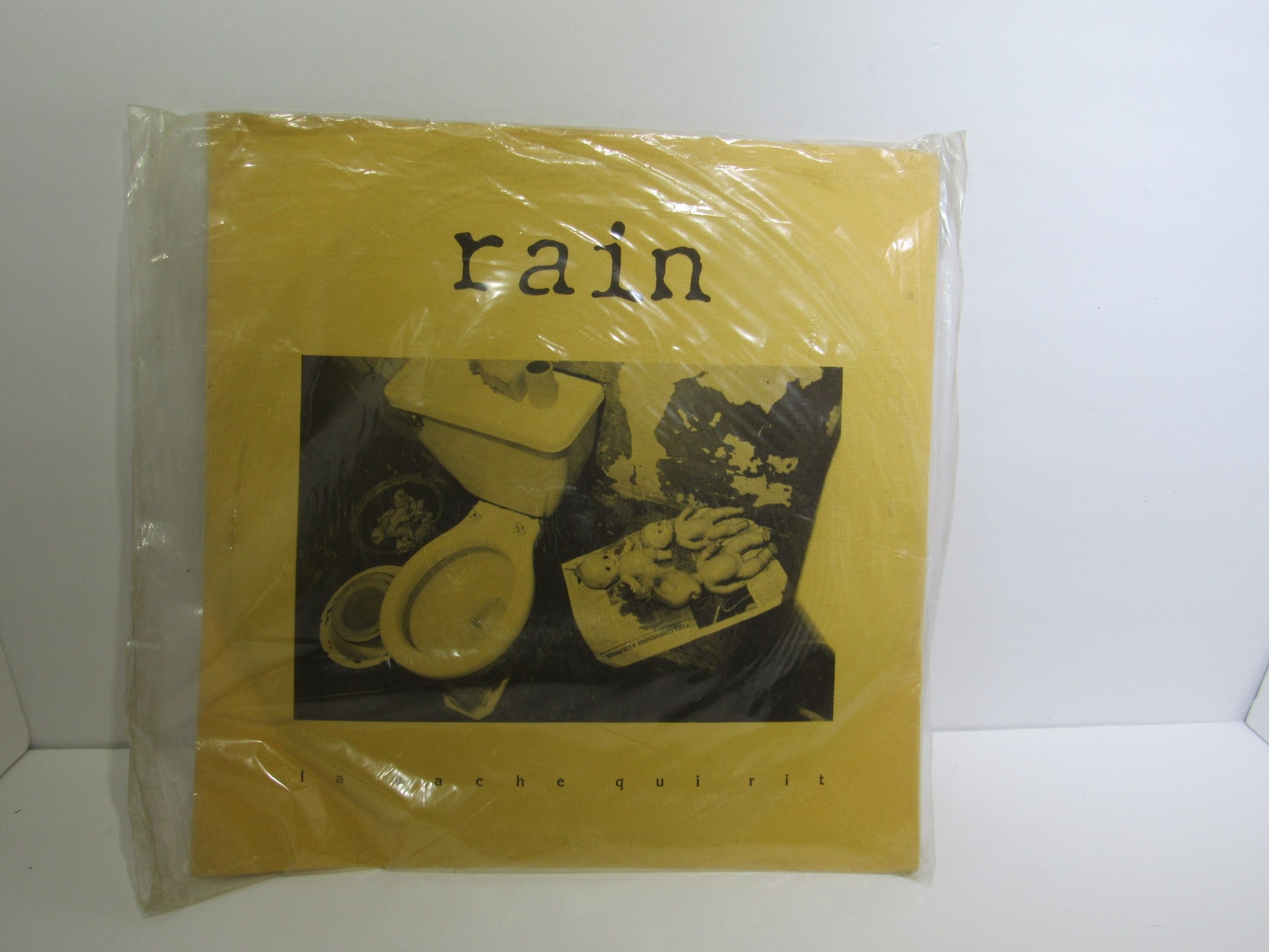 Front cover of the Rain La Vache Qui Rit LP by Peterbilt Records, showcasing a yellow design with a black and white image, released in 1990, graded VG.