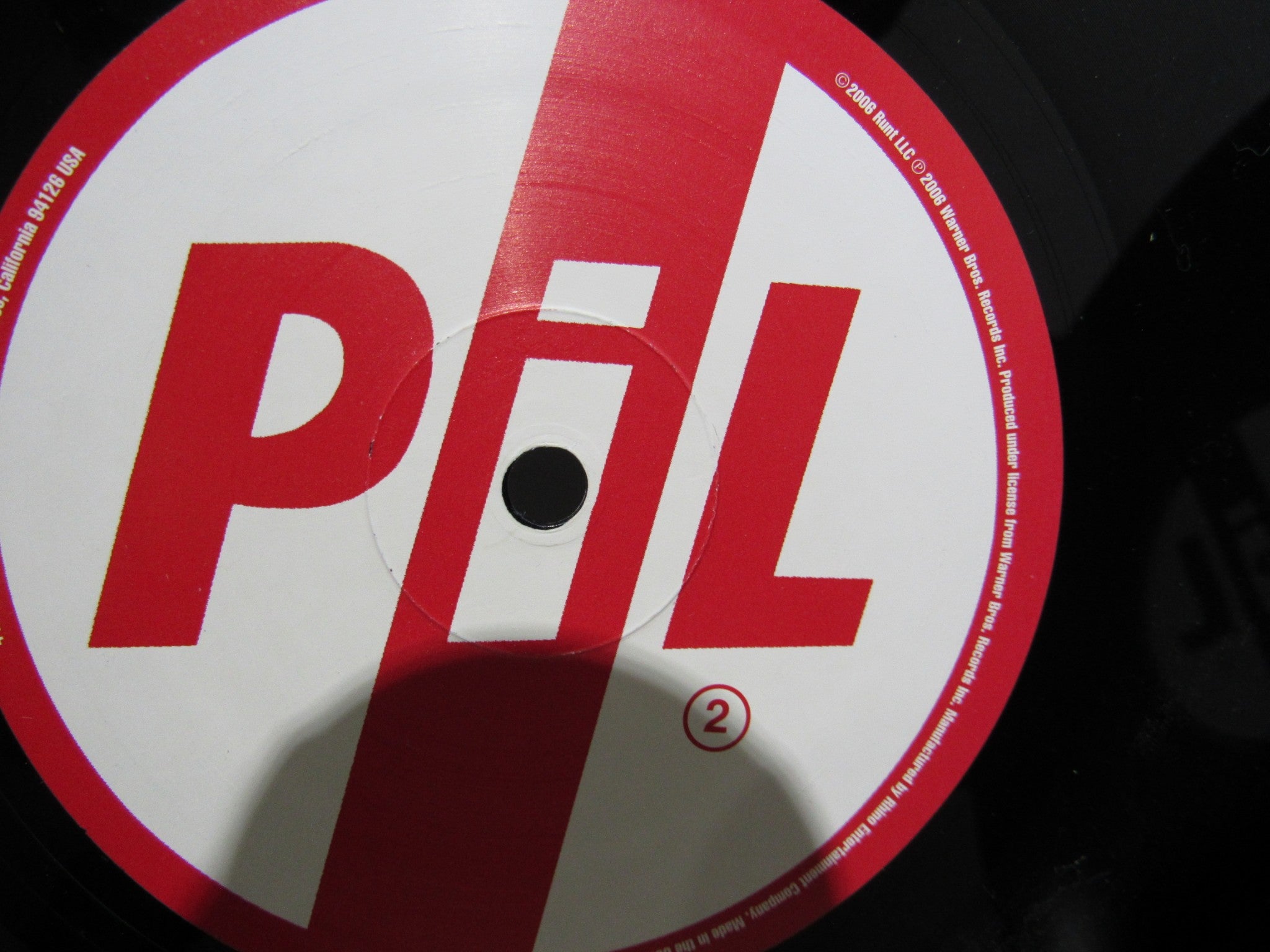 Close-up view of the vinyl label for Public Image Limited Metal Box 4 Men With Beards ‎– 4M 500 3 x 12" Vinyl LP, featuring the iconic PiL logo in red and white.