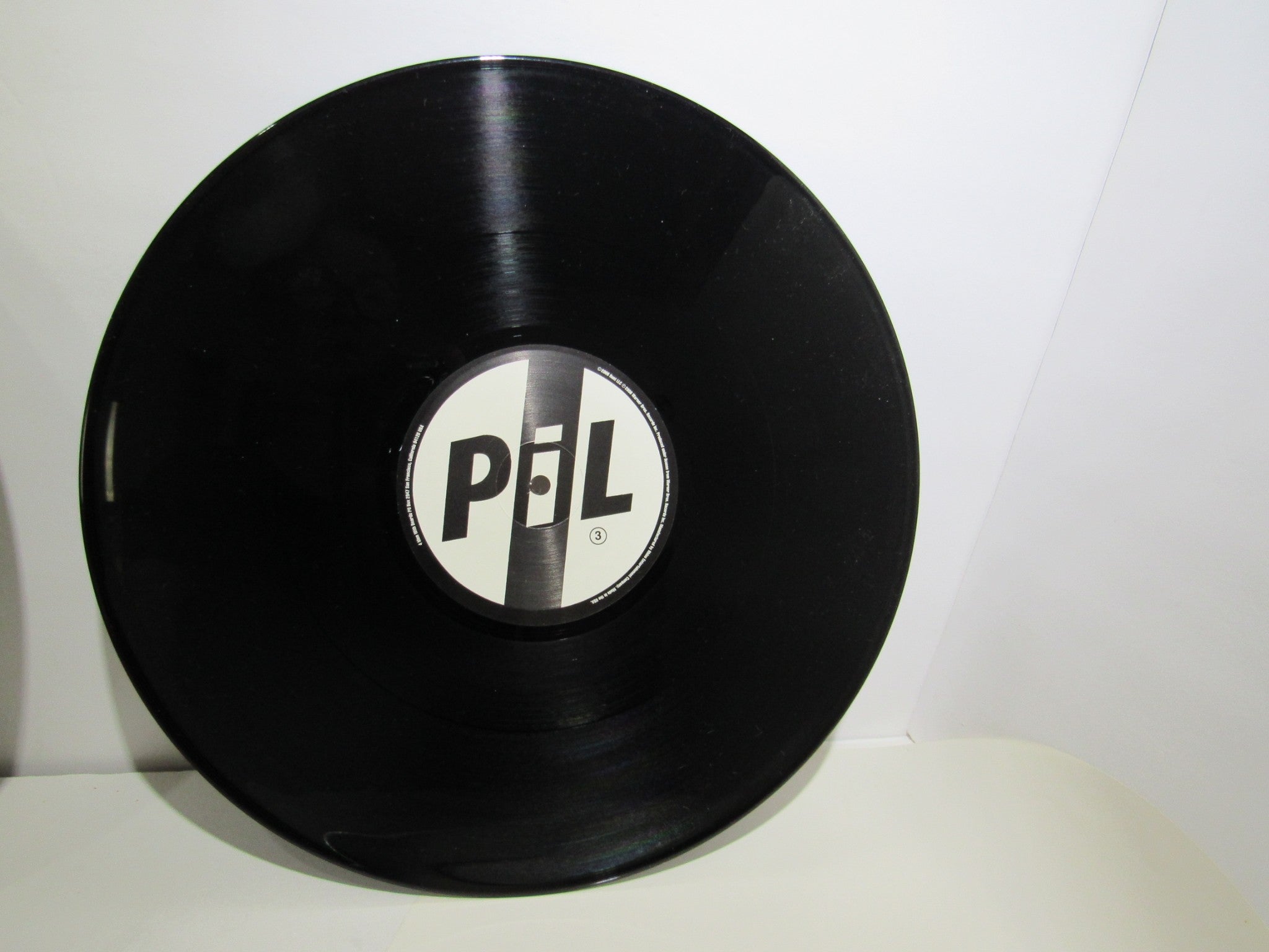 Top-down view of Public Image Limited Metal Box 4 Men With Beards ‎– 4M 500 3 x 12" Vinyl LP, showcasing the black vinyl record with the PiL logo label.