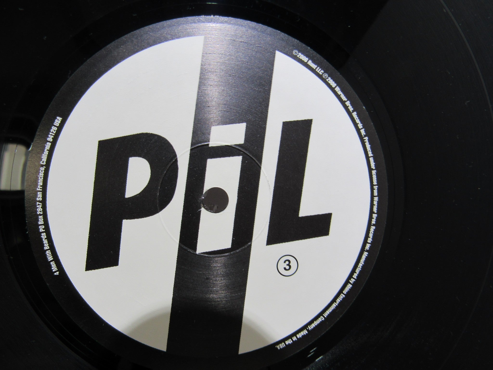 Detailed shot of the vinyl label for Public Image Limited Metal Box 4 Men With Beards ‎– 4M 500 3 x 12" Vinyl LP, highlighting the design with the PiL name in bold.