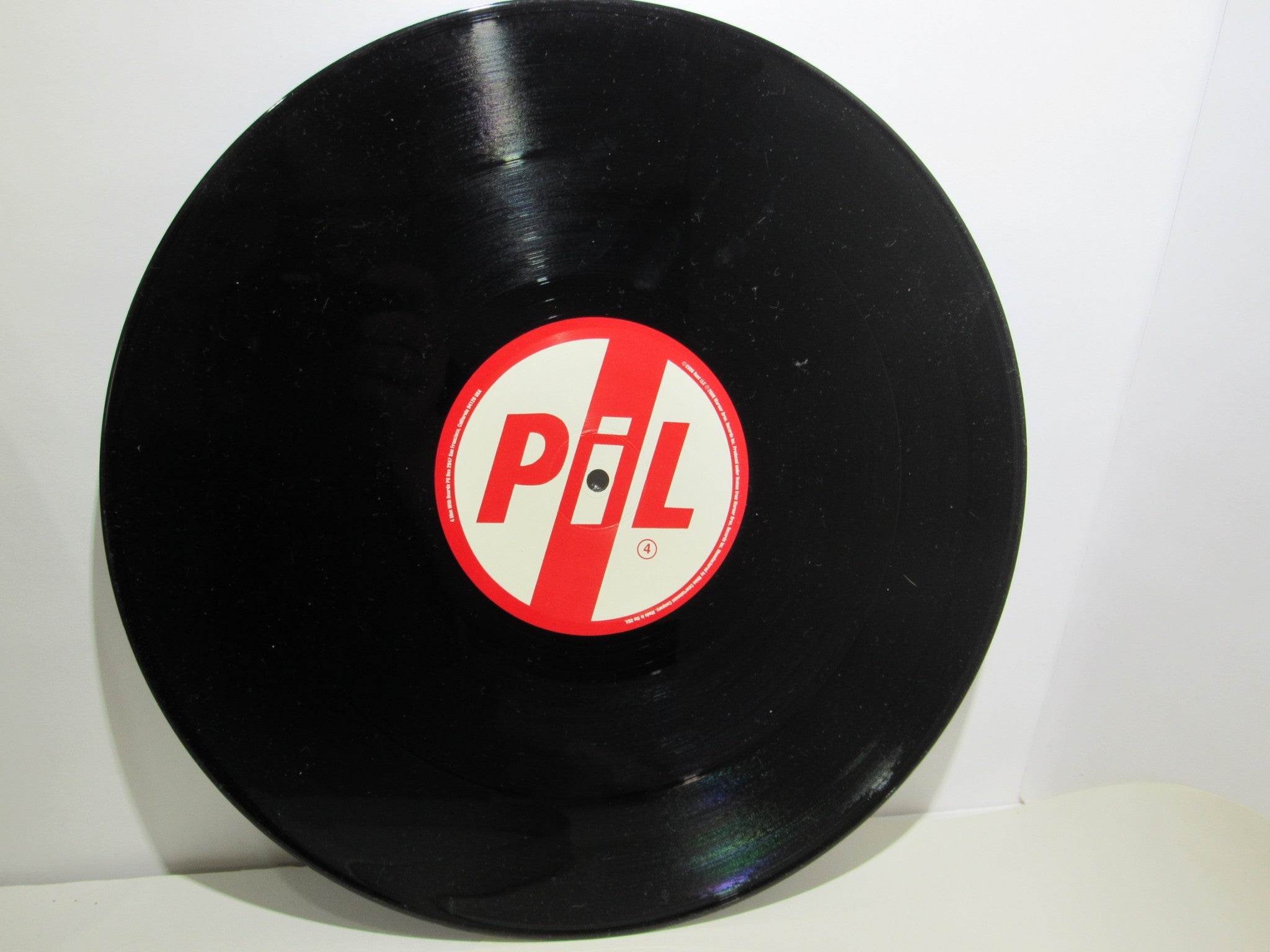 Angle view of Public Image Limited Metal Box 4 Men With Beards ‎– 4M 500 3 x 12" Vinyl LP, featuring the black vinyl with a red and white PiL label.