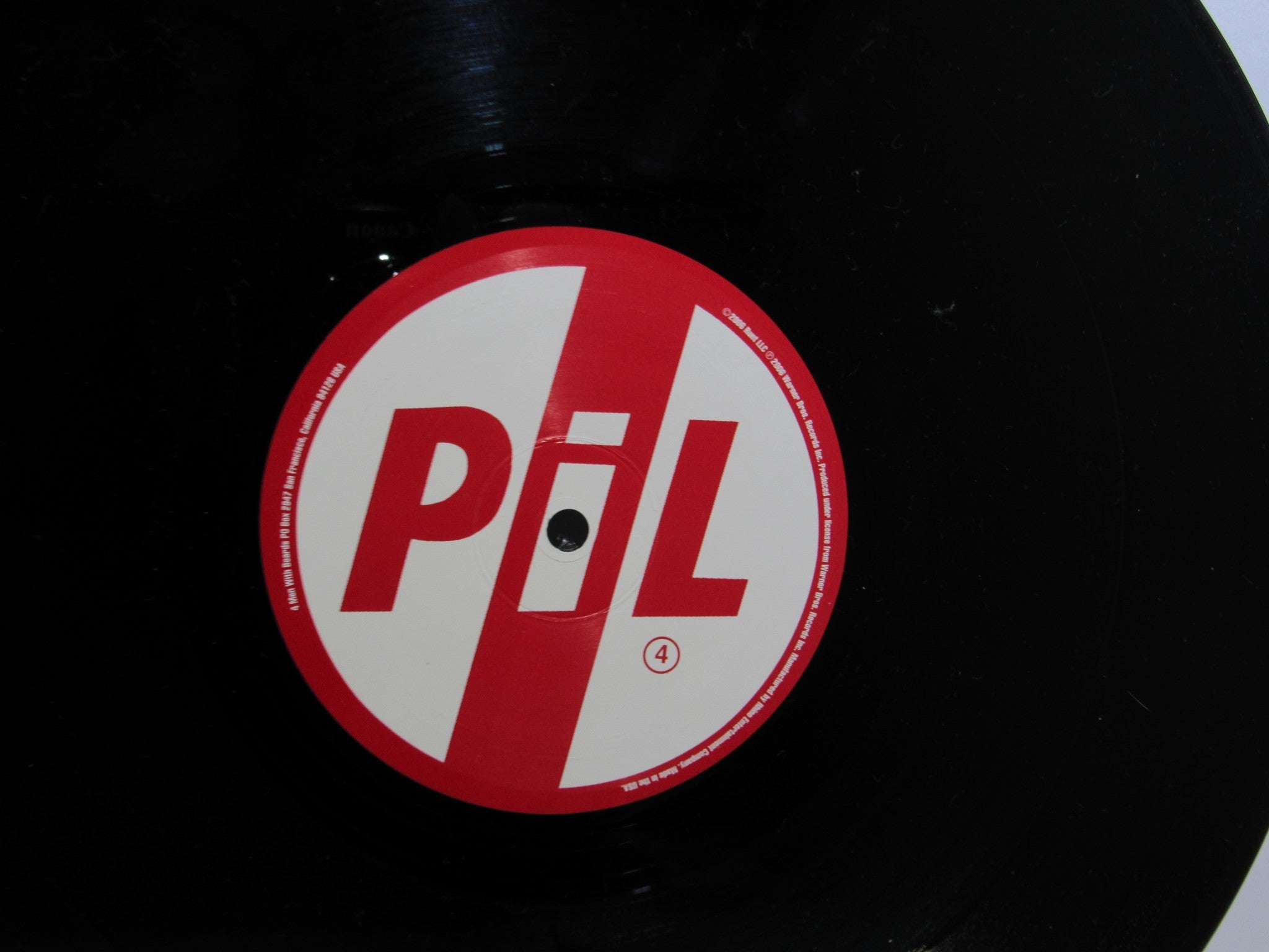Close-up of the vinyl label for Public Image Limited Metal Box 4 Men With Beards ‎– 4M 500 3 x 12" Vinyl LP, showcasing the number '4' in the design.