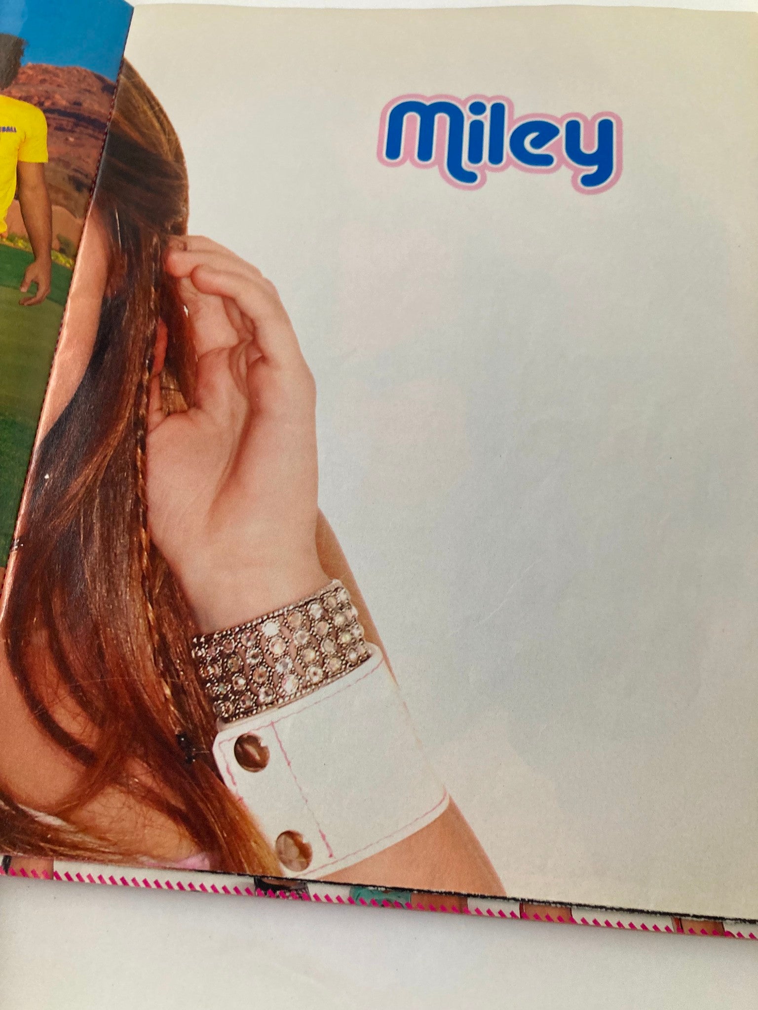 Page from Tiger Beat Magazine October 2007 featuring a close-up of Miley Cyrus's stylish bracelet with a vibrant background.