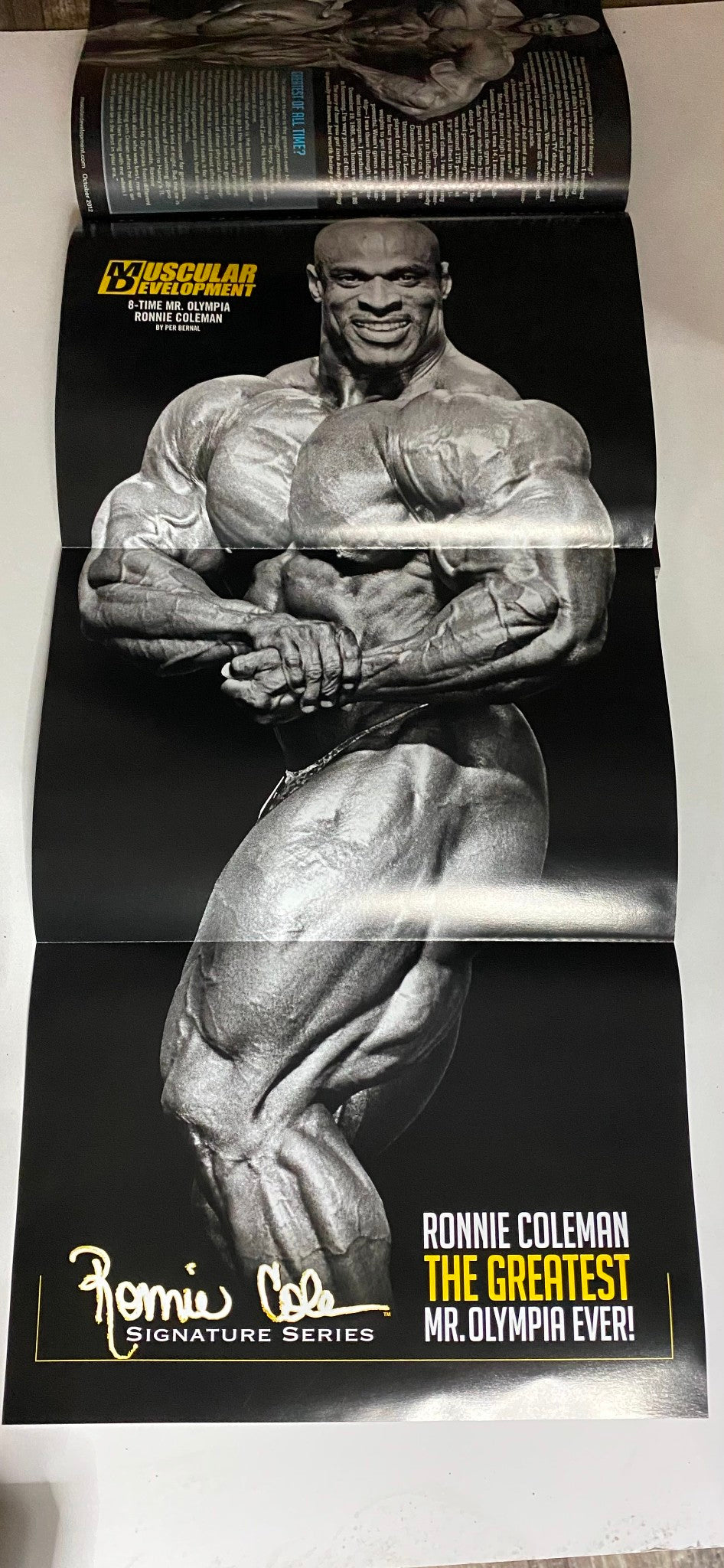 Poster inside Muscular Development Magazine October 2012 featuring Ronnie Coleman, emphasizing his title as the Greatest Mr. Olympia and showcasing his impressive physique.