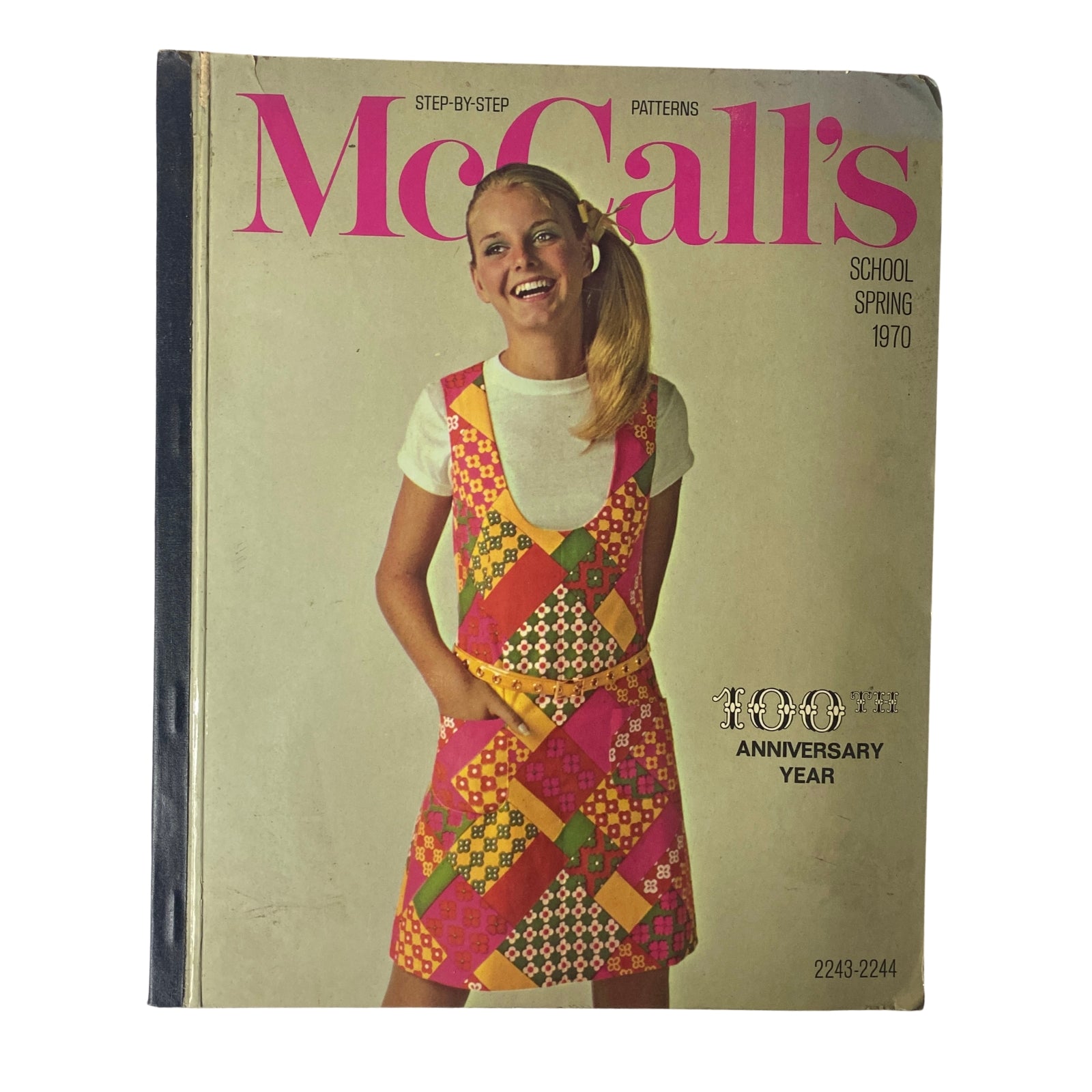 1970 McCall's School Spring Huge Store Retail Counter Catalog cover featuring a girl wearing a colorful fashion apron dress with a patchwork design, representing vibrant 1970s youth fashion.
