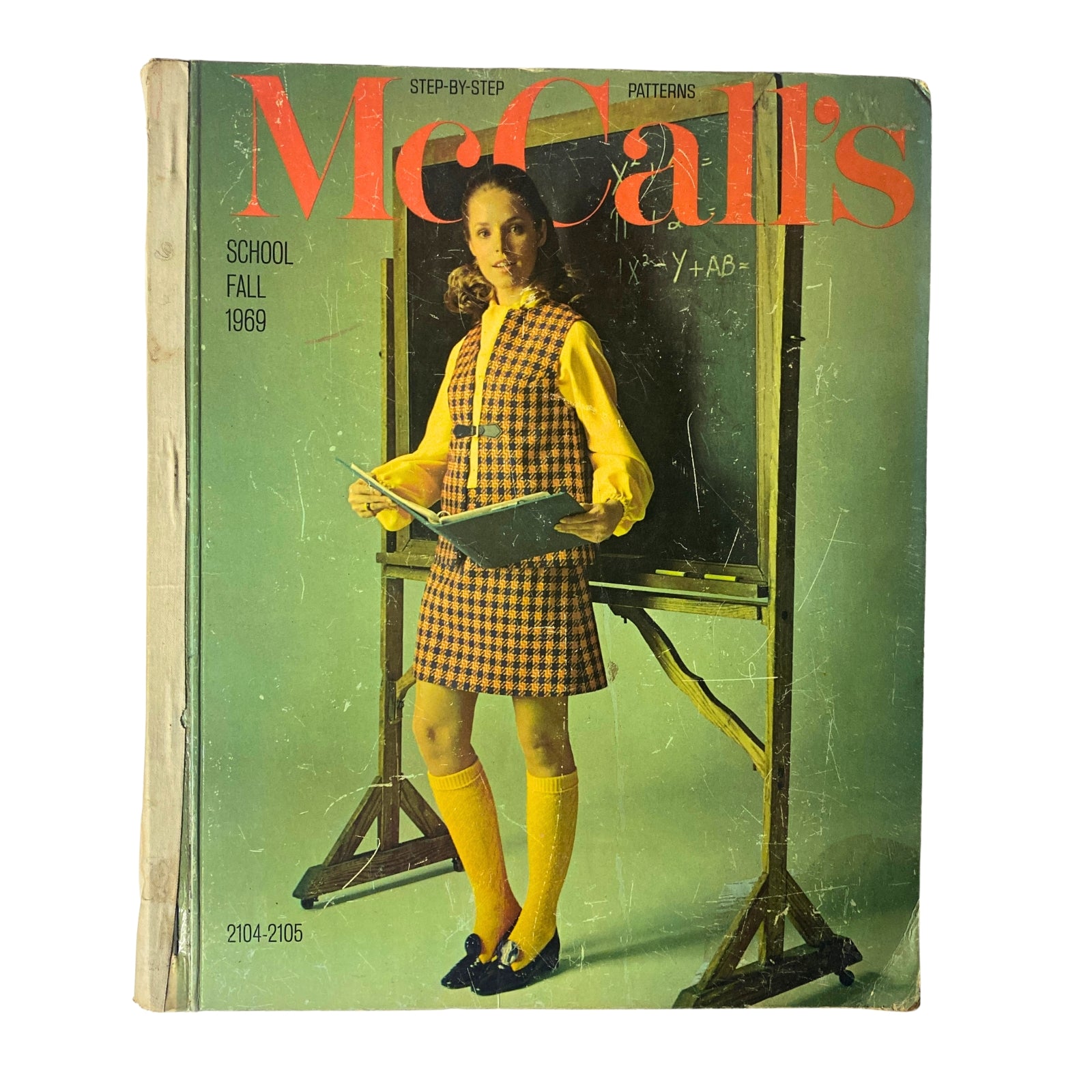 1969 McCall's School Fall Huge Store Retail Counter Catalog cover featuring a girl in a vintage plaid dress with knee-high socks, holding a book, standing in front of a chalkboard.