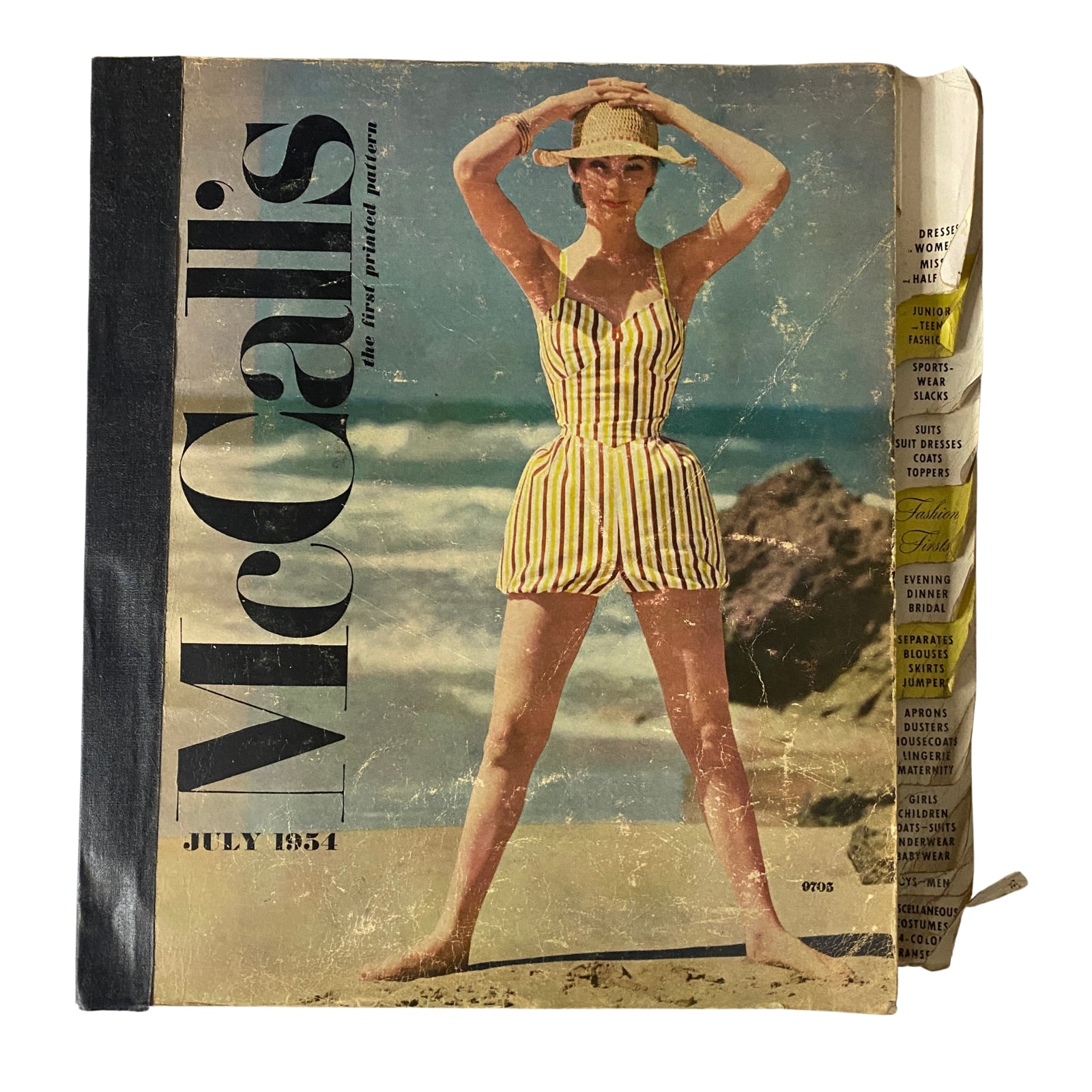 Cover of the 1954 July McCall's The First Printed Pattern Catalog showcasing a model in a striped swimsuit at the beach.
