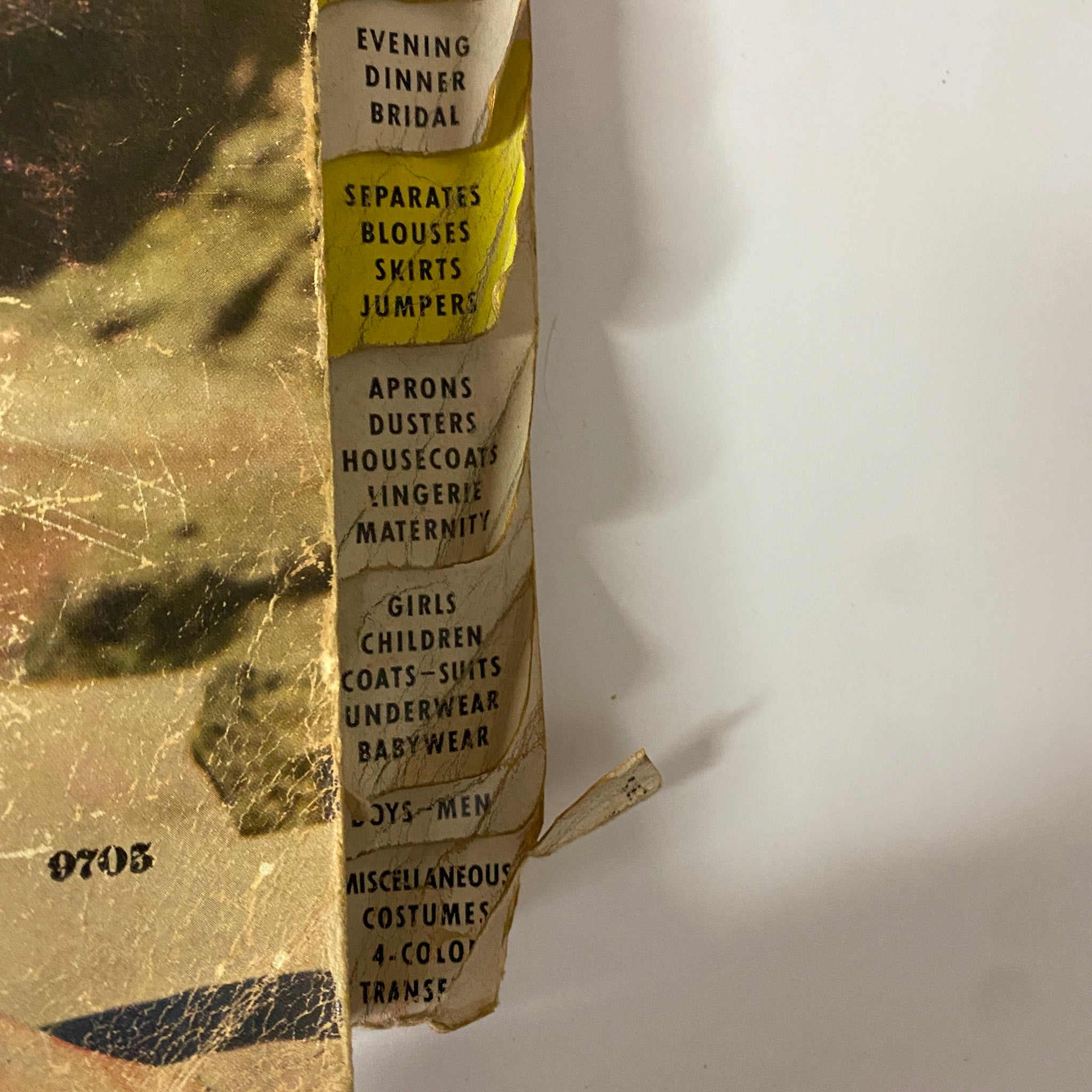 Close-up of the edge of the 1954 July McCall's The First Printed Pattern Catalog, featuring listings for separates, blouses, skirts, and children's wear.