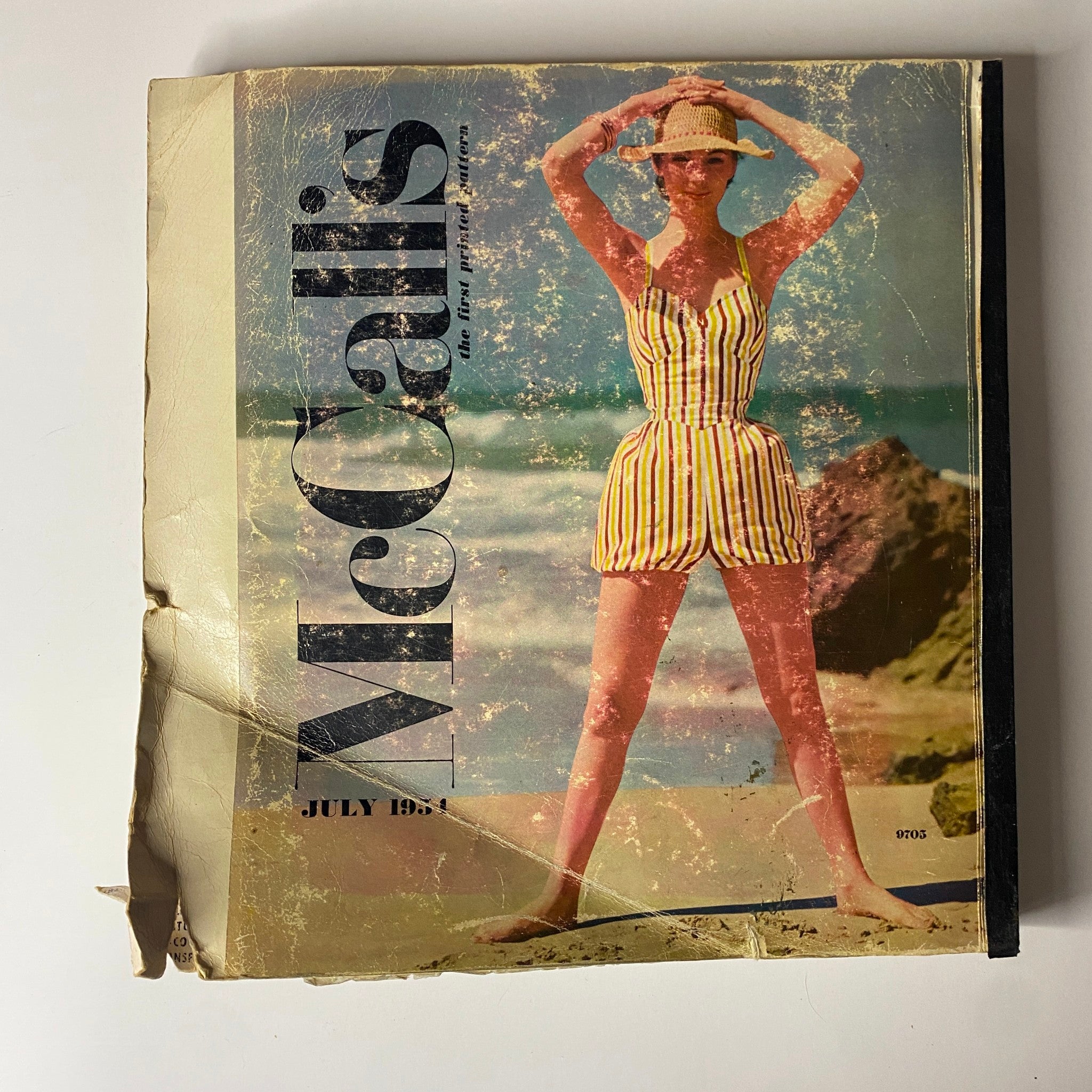 Cover image of the 1954 July McCall's catalog showing a model in a vintage swimsuit on the beach, marking a pivotal moment in home sewing pattern history.