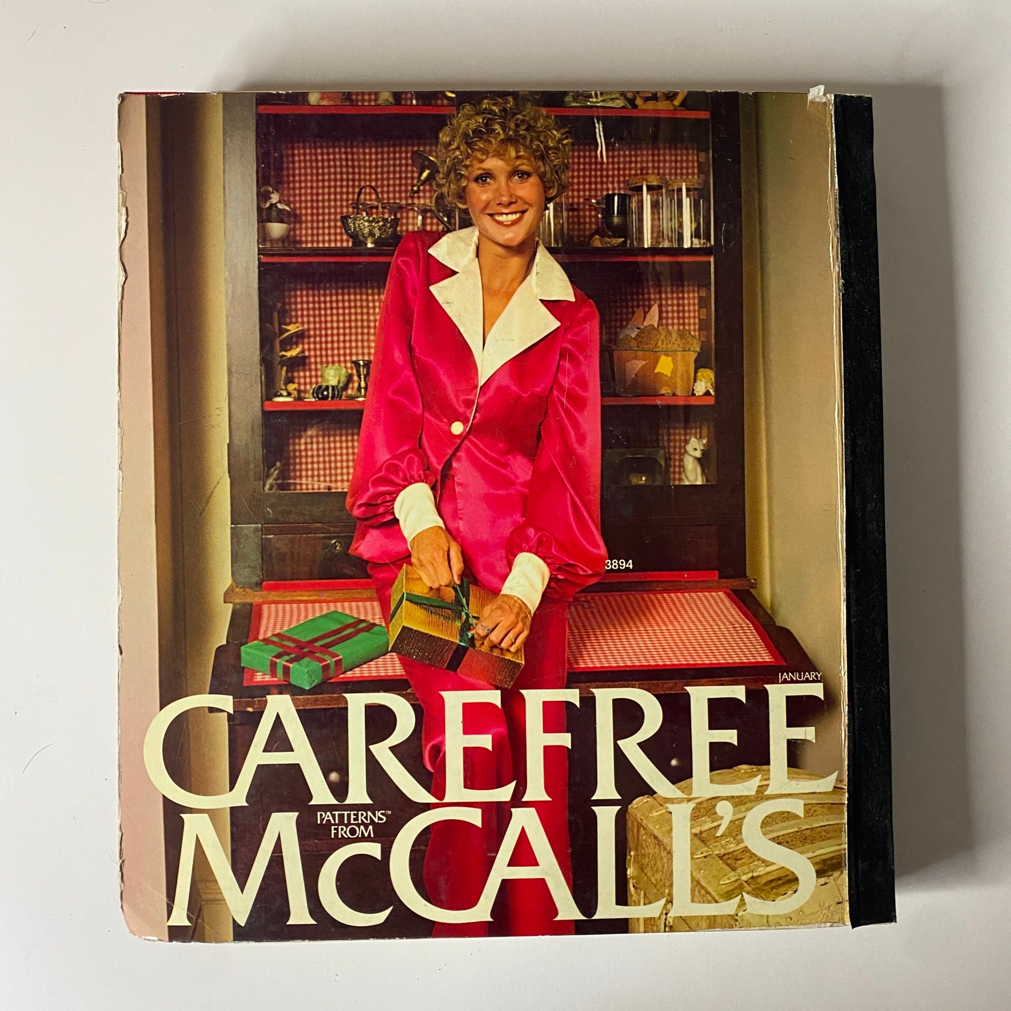 1973 January Carefree McCall's Huge Store Retail Counter Catalog cover featuring a woman in a bright pink outfit with stylish details, promoting the selection of sewing patterns from the 1970s for fashionable and timeless looks.