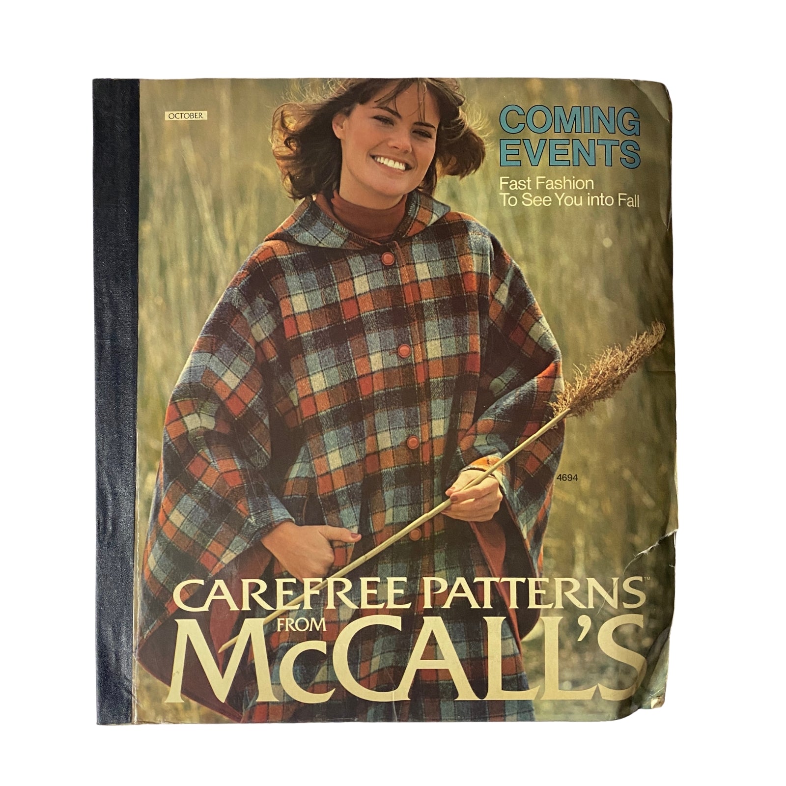 Cover page of 1975 October Carefree Patterns from McCall's featuring a model in a plaid cape holding a wheat stalk, showcasing retro fashion style.