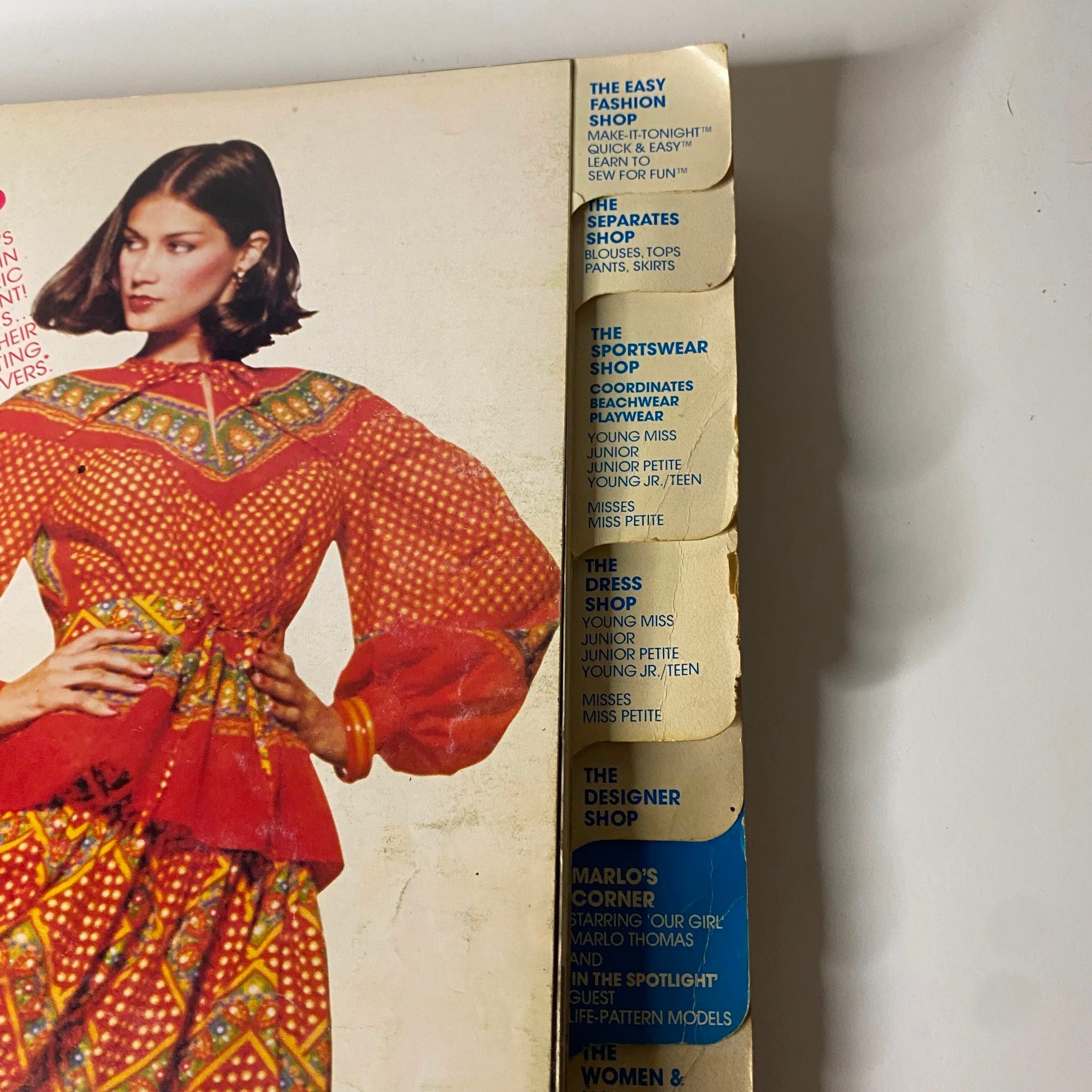 Detailed view of the side of the 1970s March Carefree Patterns from McCall's Catalog, displaying pattern categories and featuring a model in a vibrant red and patterned outfit.