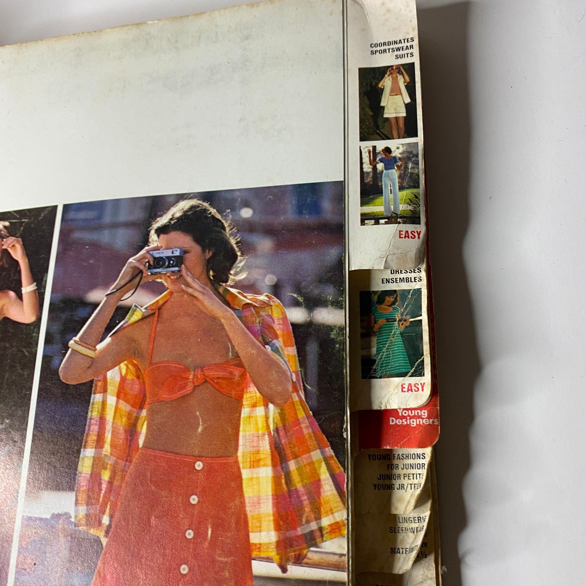 Side view of the 1974 June Butterick Catalog showing the spine with a listing of various fashion designs. The catalog focuses on coordinates, sportswear suits, and features 1970s inspired clothing suitable for home sewing.