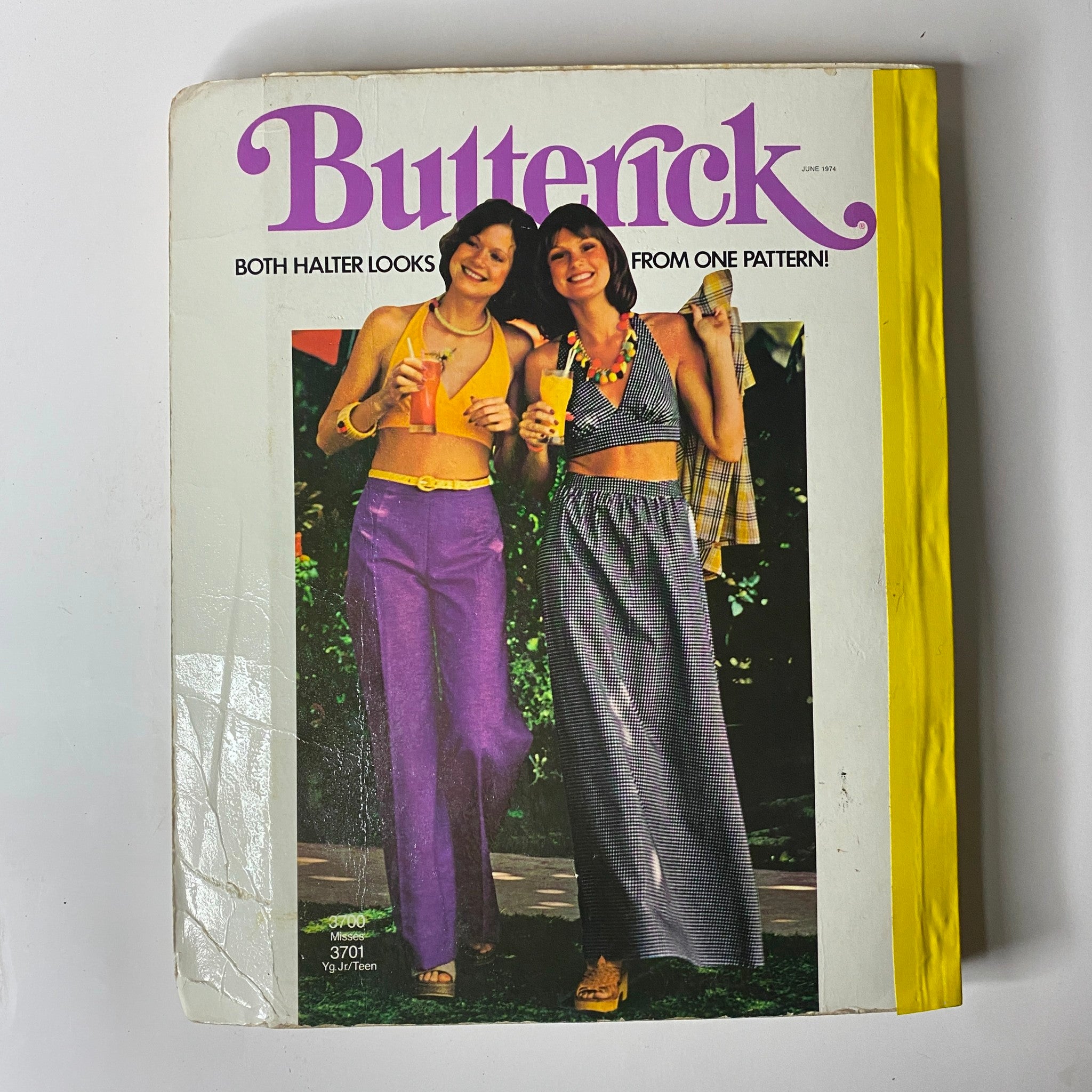 1974 June Butterick Catalog cover featuring two young women in halter outfits, promoting versatile sewing patterns for summer fashion.