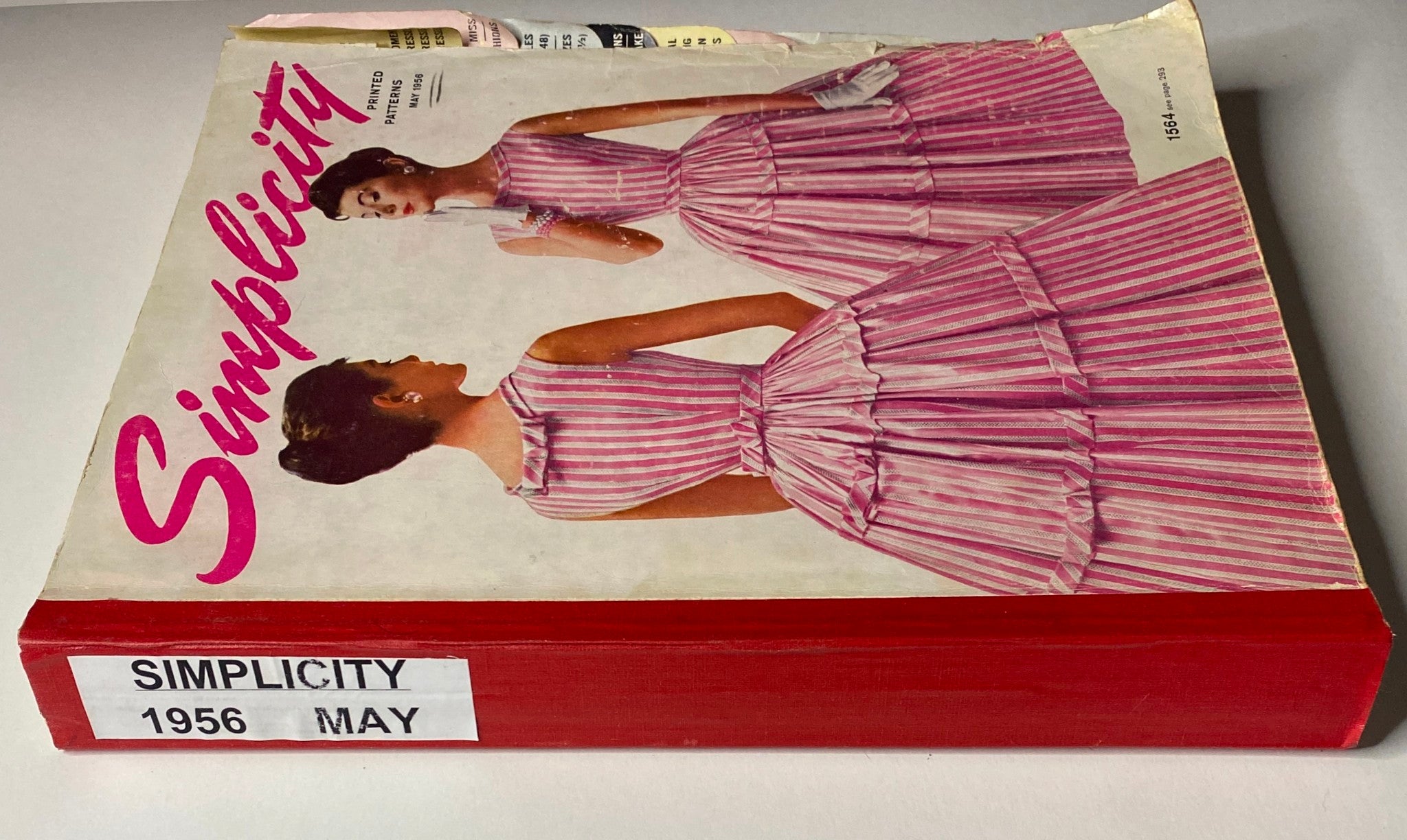 Cover of the 1956 May Simplicity Sewing Pattern Catalog, featuring elegant vintage dress designs in pink stripes, highlighting mid-century fashion trends.