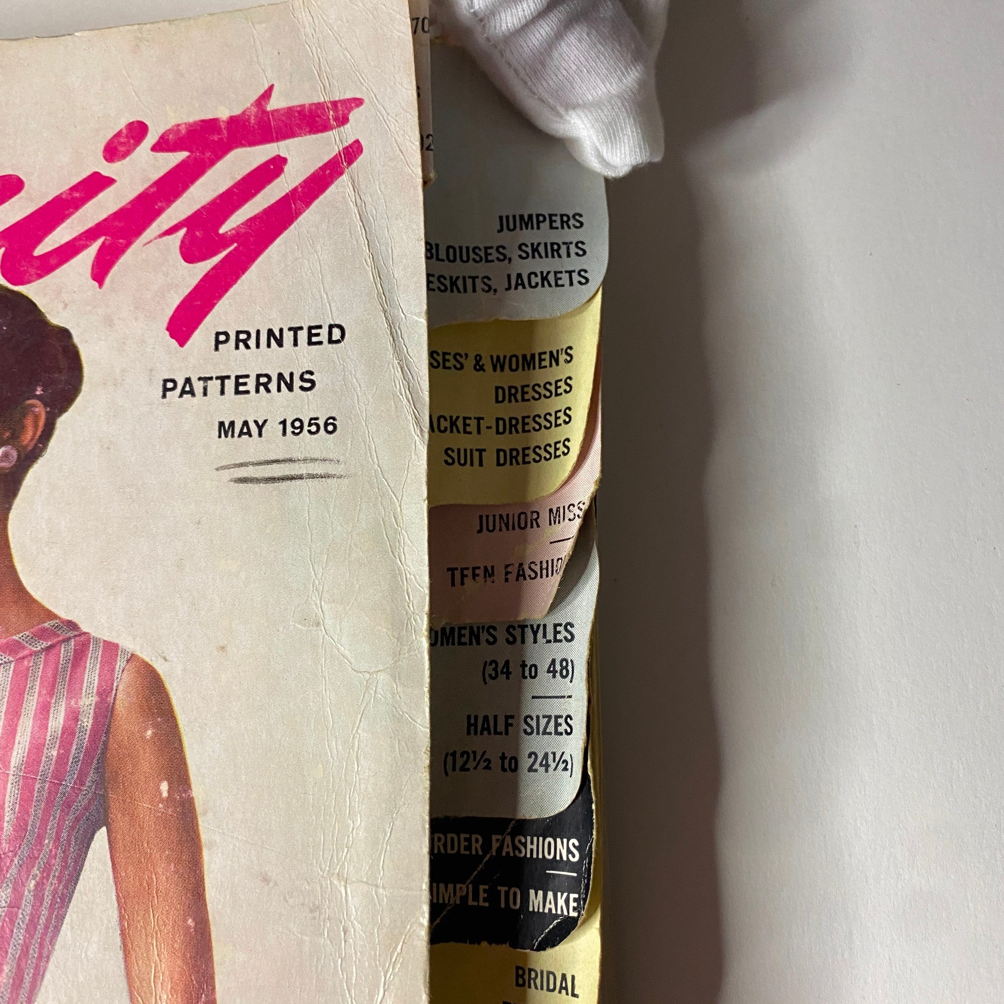 Close-up of the 1956 May Simplicity Sewing Pattern Catalog cover, showcasing details of printed patterns available in various women's dresses, emphasizing vintage sewing styles.