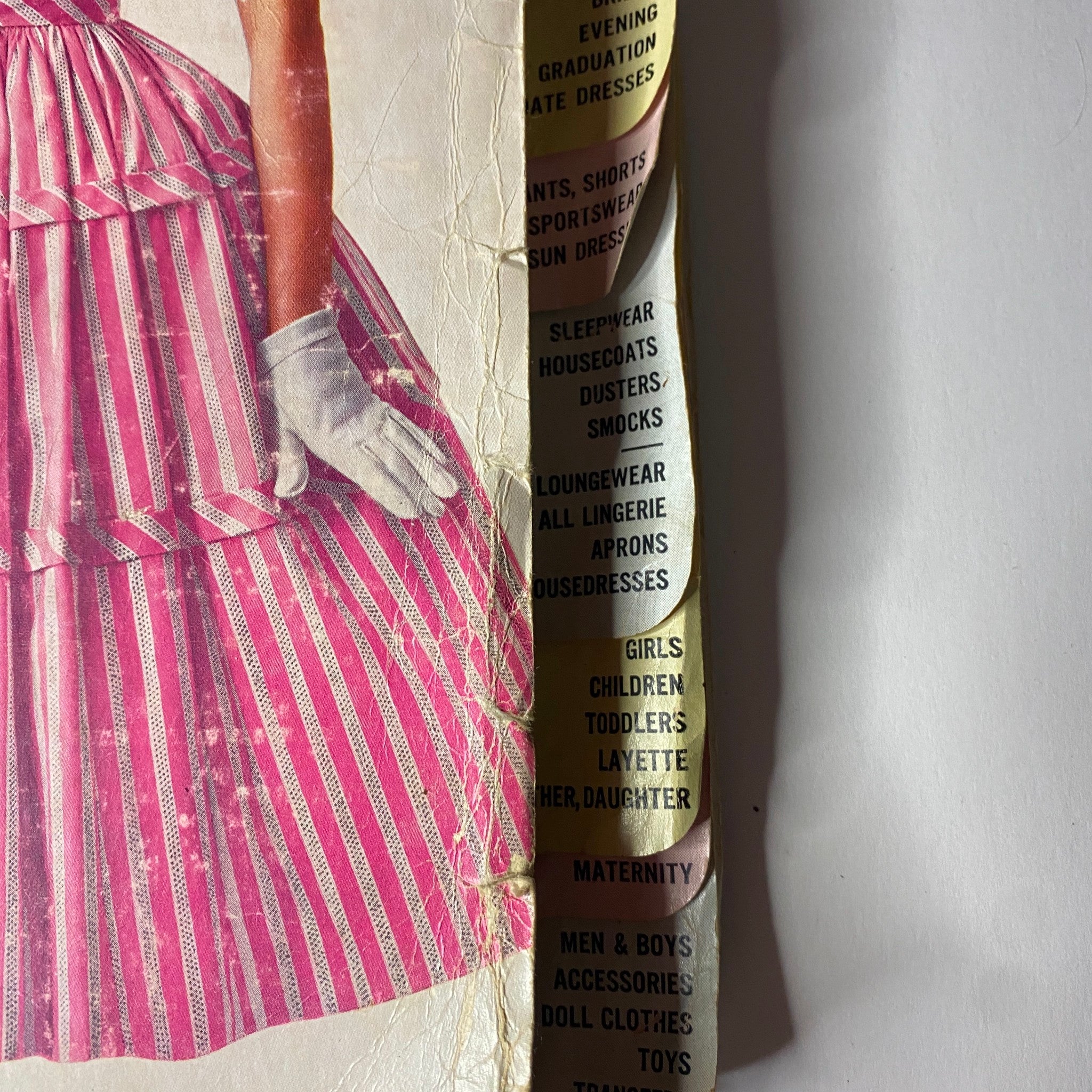 Detailed view of the 1956 May Simplicity Sewing Pattern Catalog spine, with visible categories for clothing patterns including dresses, sleepwear, and maternity.