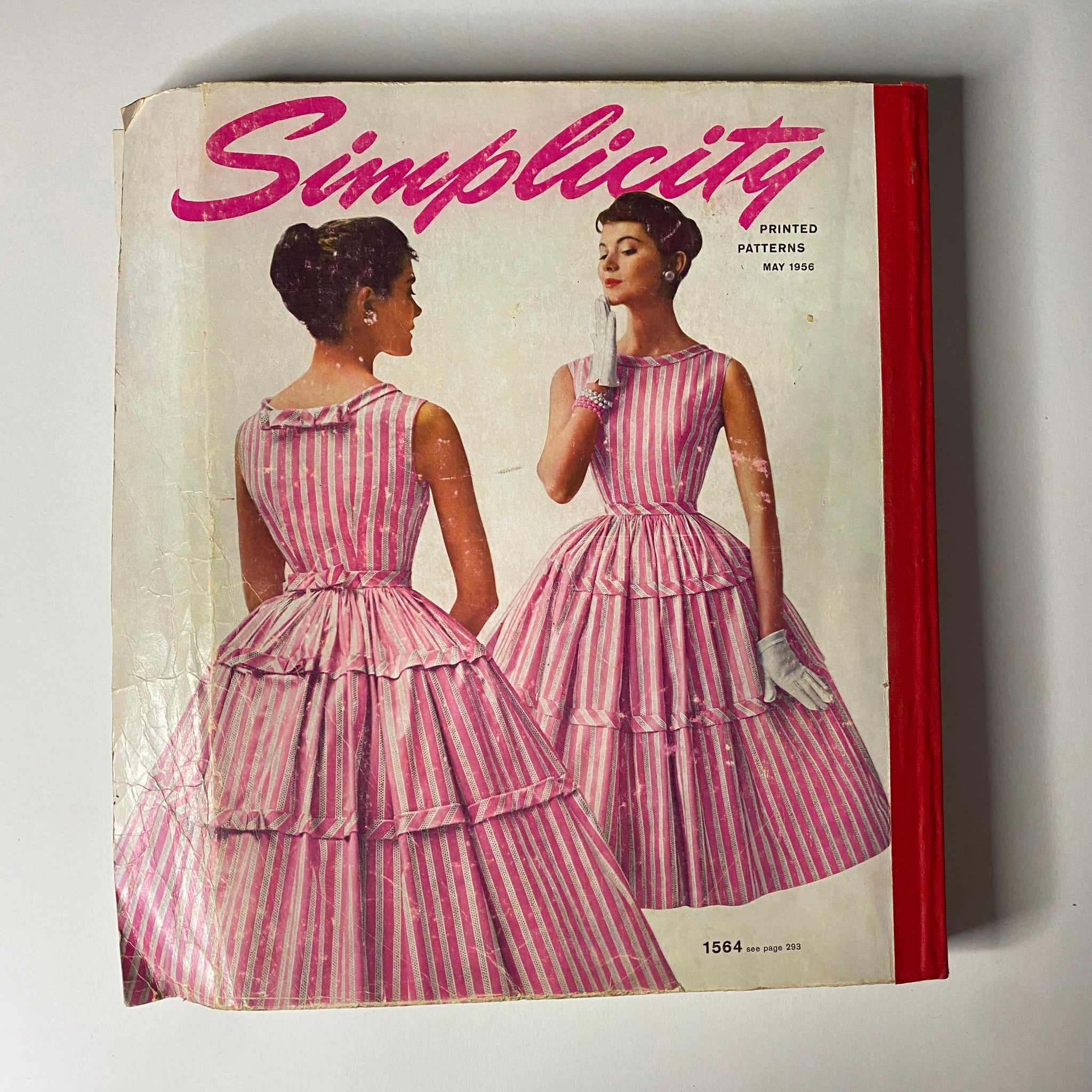 1956 May Simplicity Sewing Pattern Catalog cover featuring stylish models in pink striped dresses, emphasizing mid-century fashion trends and elegance.