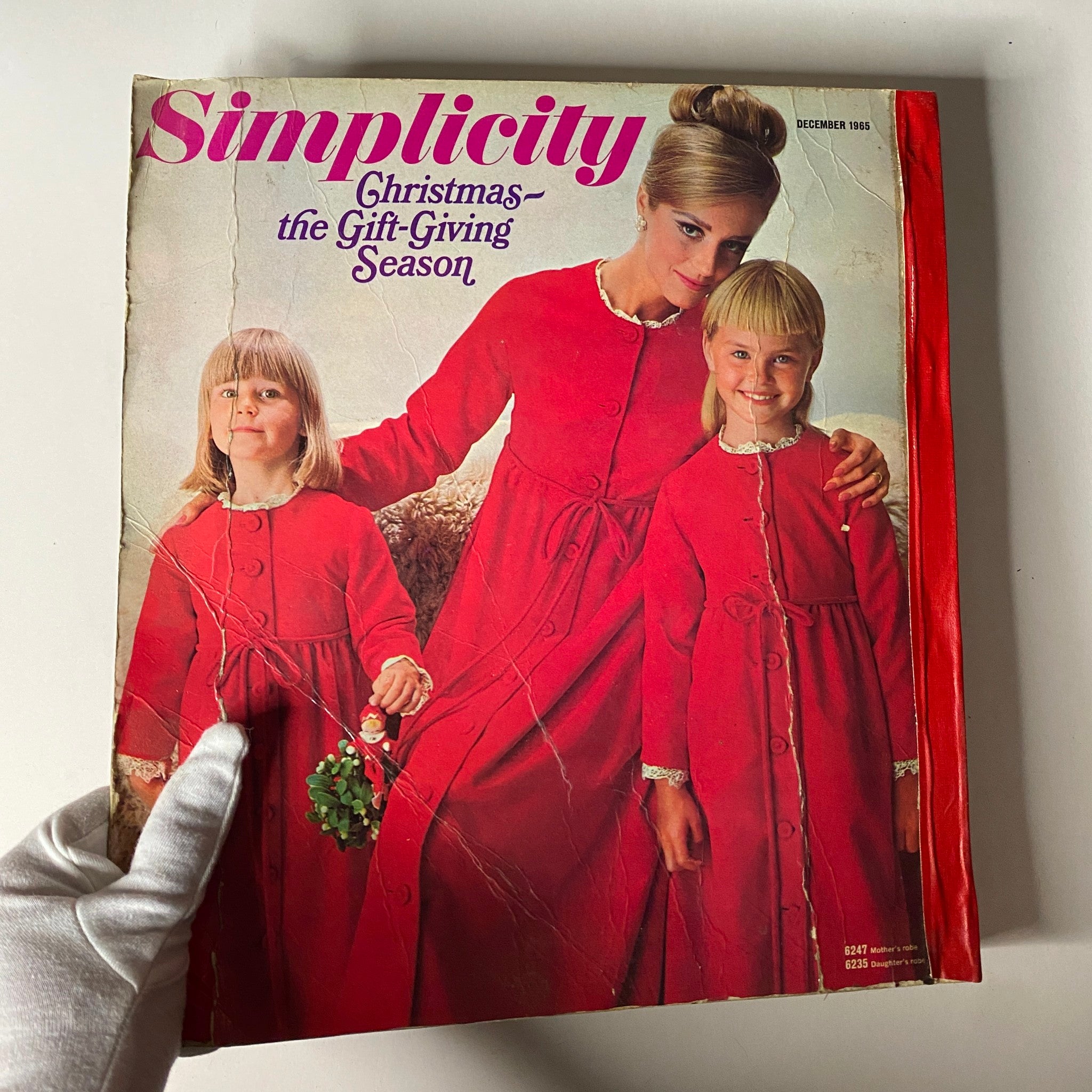 Front cover of the 1965 December Simplicity Christmas Catalog showcasing a mother and daughter in matching red outfits, emphasizing Christmas-themed sewing patterns.