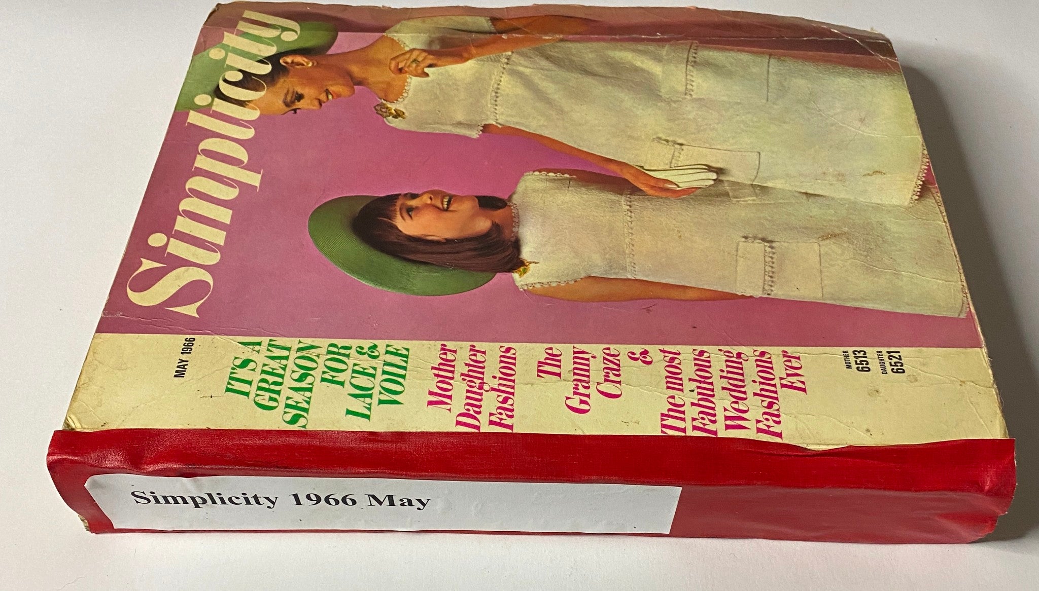 Side view of the 1966 May Simplicity Fashion Catalog, emphasizing mother and daughter fashion themes with colorful text for a nostalgic vintage collection.