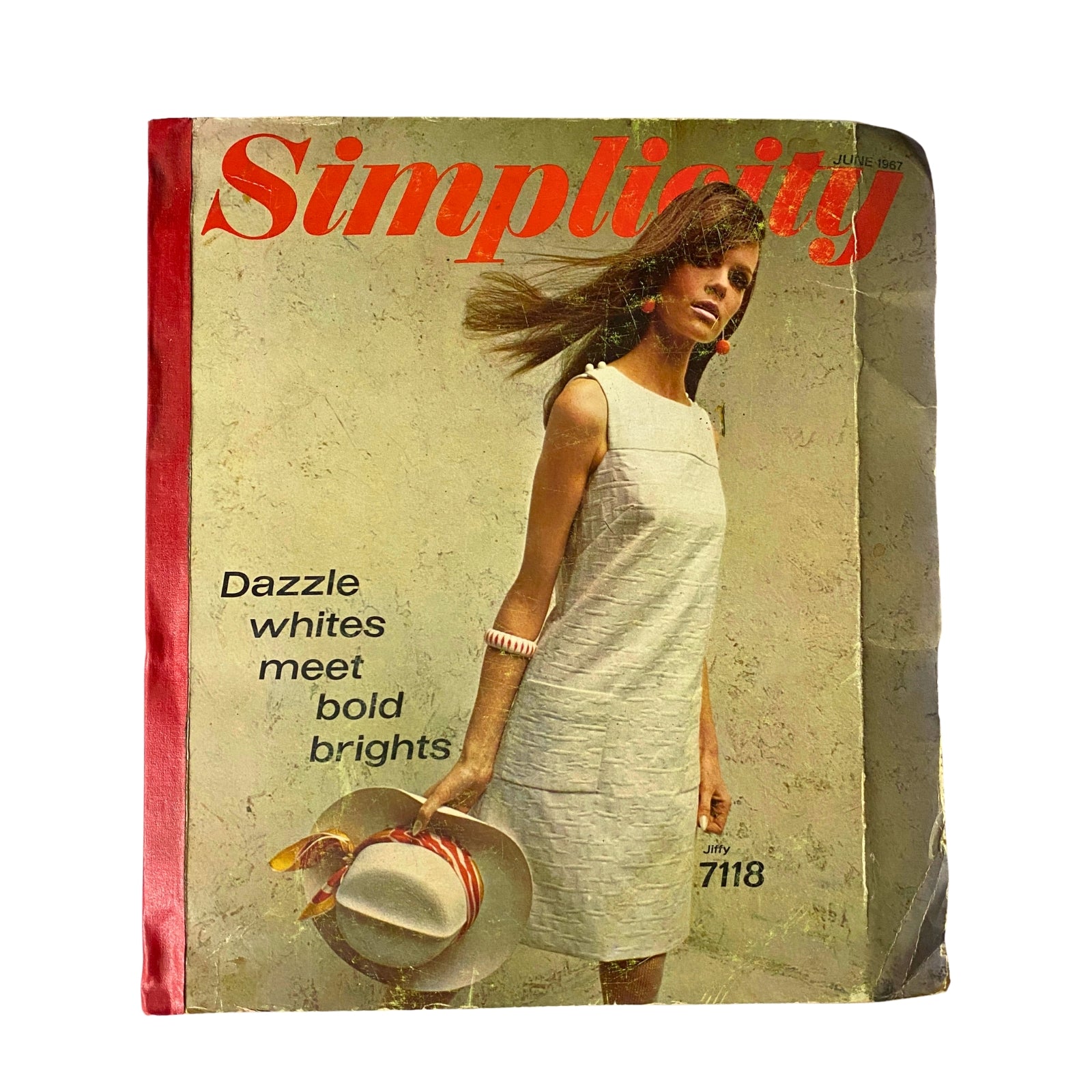 Cover of the 1967 June Simplicity Sewing Pattern Catalog featuring a model in a stylish white dress, accompanied by a hat, showcasing bold and bright fashion trends of the 1960s.