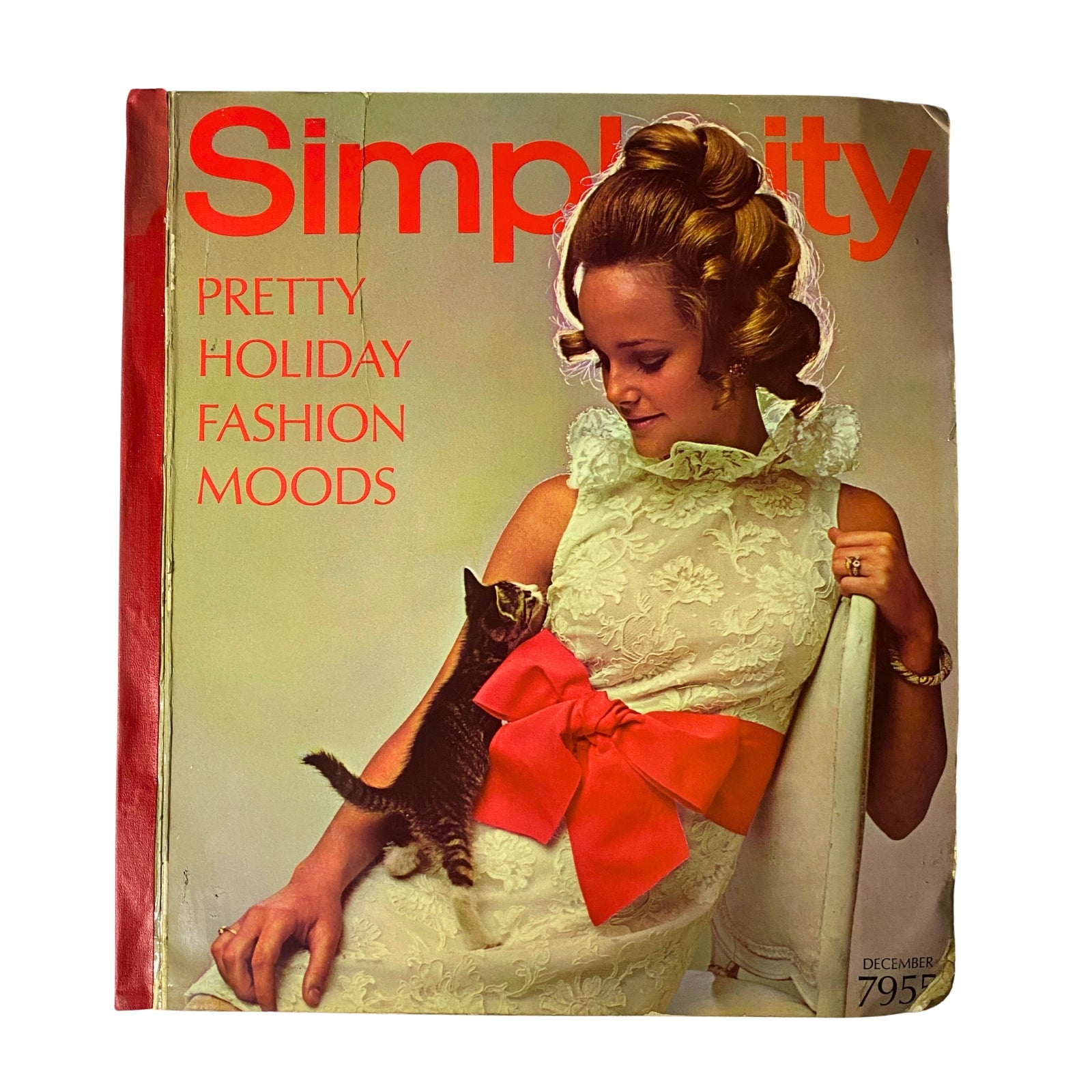 1968 December Simplicity Catalog Sewing Pattern cover featuring a woman in a floral dress with a large red bow, holding a kitten, showcasing pretty holiday fashion moods.