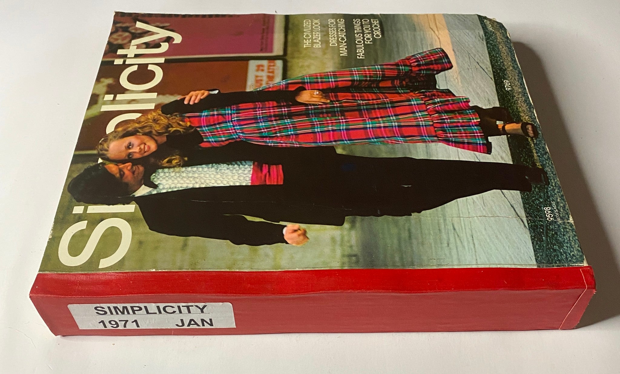 Side view of the 1971 January Simplicity Catalog showing the spine with a label indicating 'Simplicity 1971 JAN'. The cover features a couple in classic '70s attire, emphasizing a vintage fashion aesthetic.