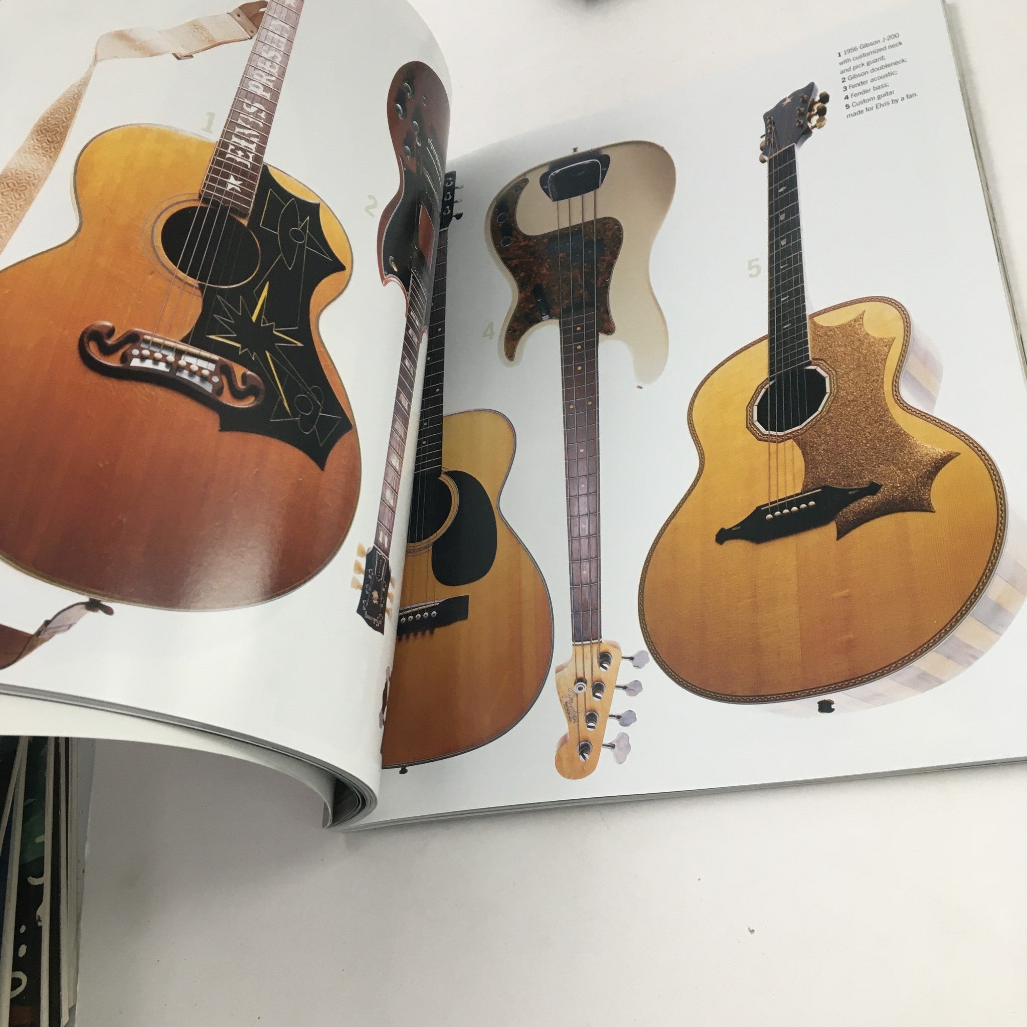 Spread from 'Elvis Presley Then & Now Official Graceland 25th Anniversary Collector's Edition' showing various iconic acoustic guitars owned by Elvis Presley.