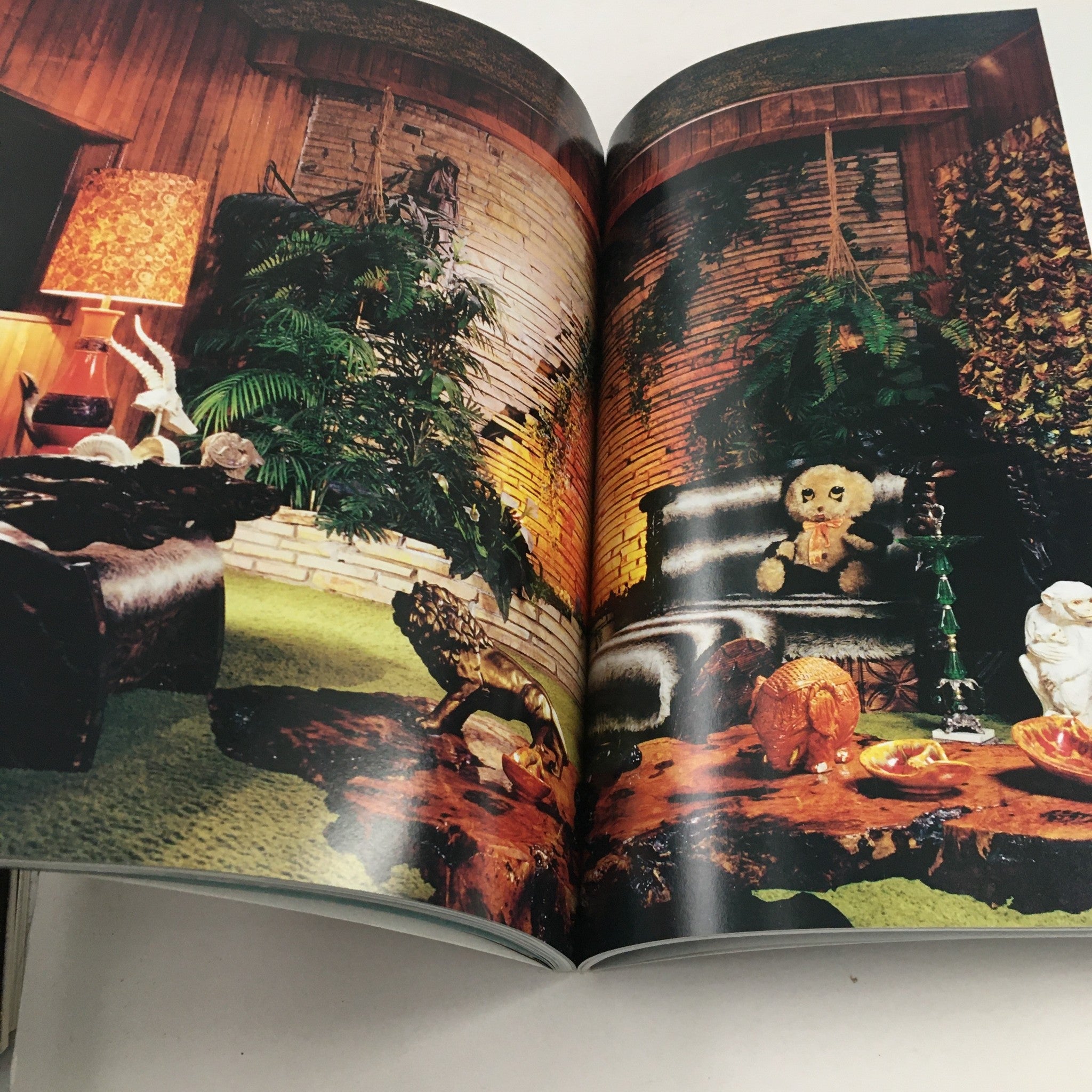 Interior page from 'Elvis Presley Then & Now Official Graceland 25th Anniversary Collector's Edition' depicting a retro living room setting with unique decor and a teddy bear.