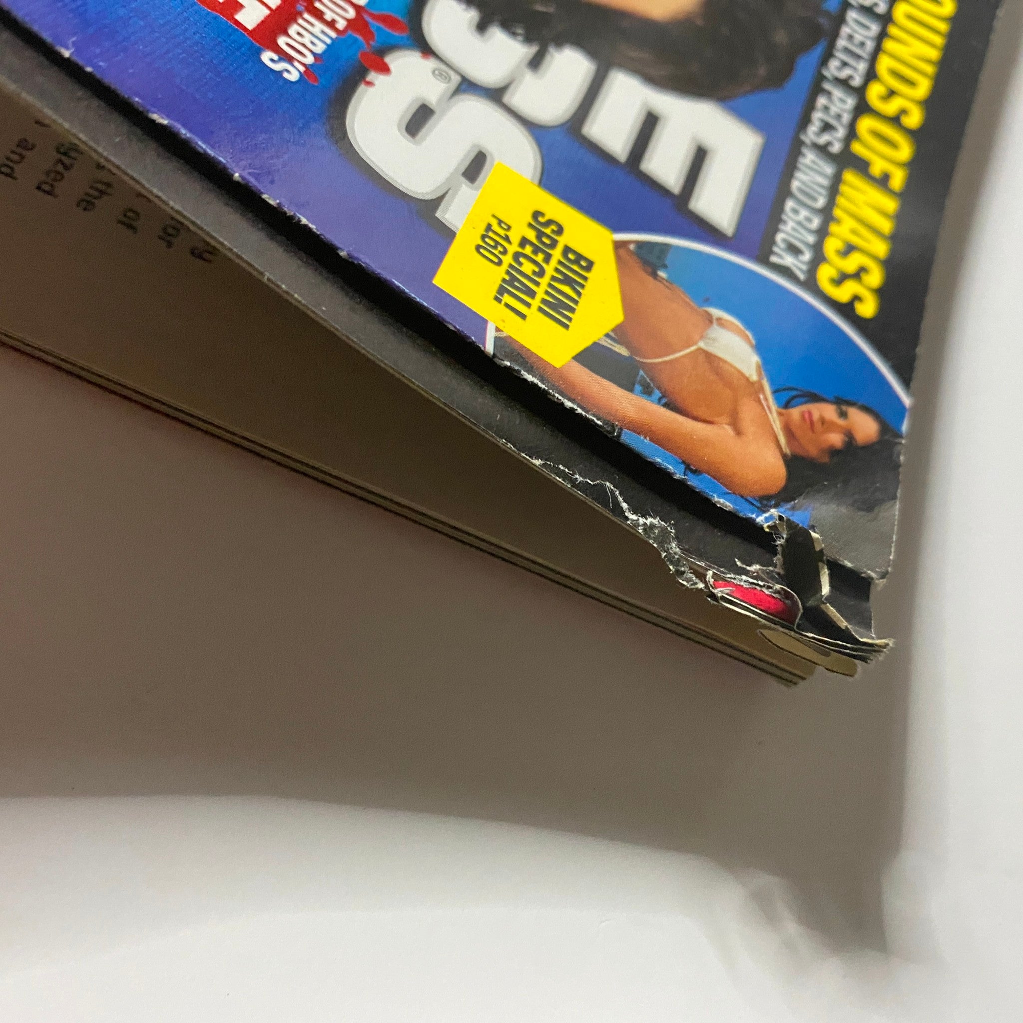 Close-up view of the spine and cover edge of the Muscle & Fitness Magazine July 2011, highlighting its vintage condition.