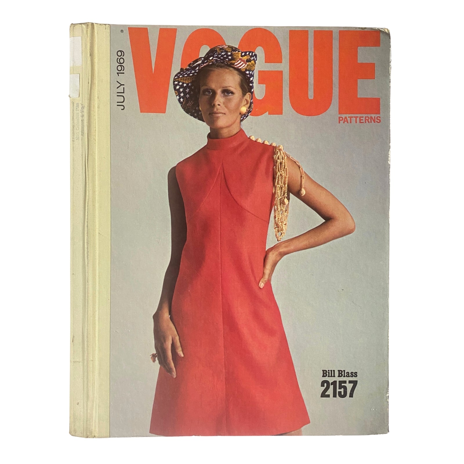 1969 Vogue Patterns July Catalog Large Store Counter Pattern Book featuring a stylish model in a red dress, showcasing late '60s fashion. Cover design includes bold orange text and a chic hat.