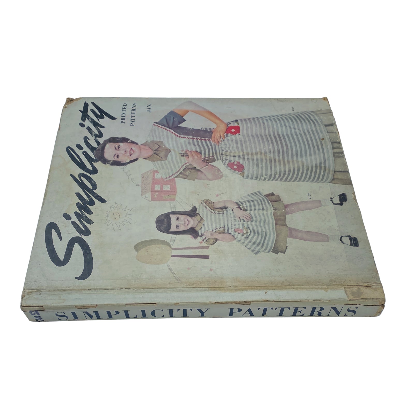 Side view of the Vintage 1952 January Simplicity Sewing Pattern Catalog, displaying a colorful cover with women and child in striped dresses, emphasizing vintage sewing styles.