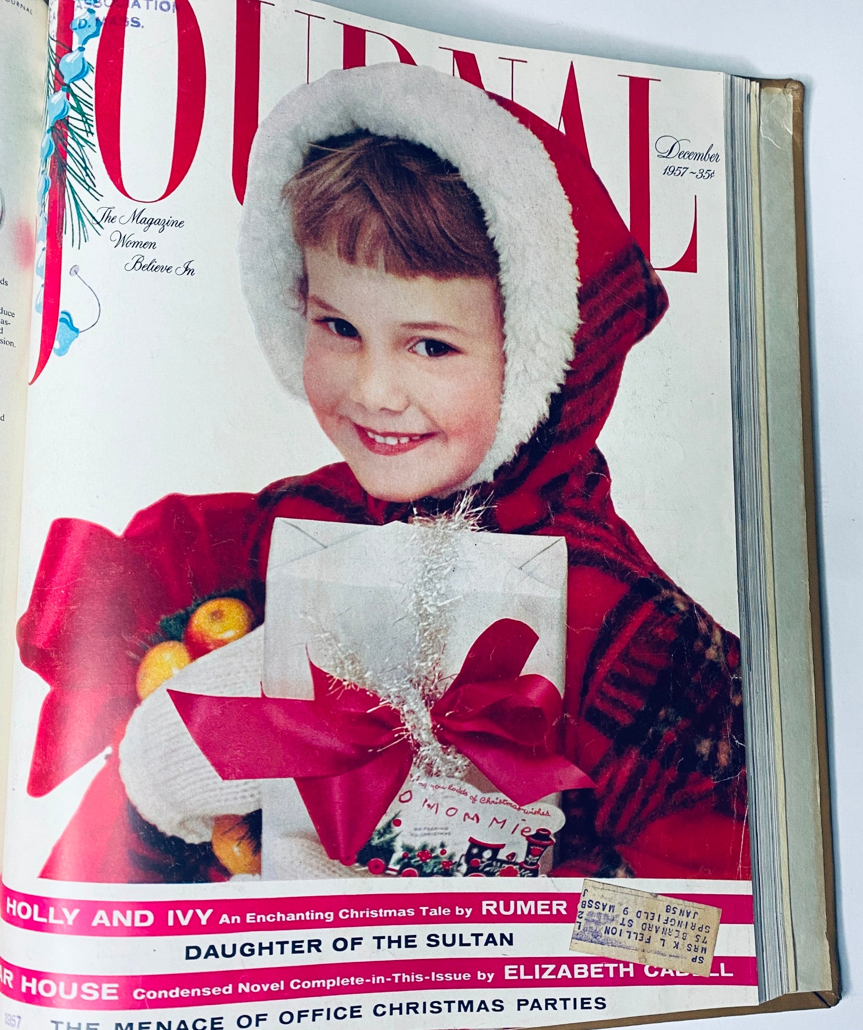 December 1957 Ladies' Home Journal cover showing a young girl in a festive outfit smiling while holding a gift, capturing the holiday spirit of the late 1950s.