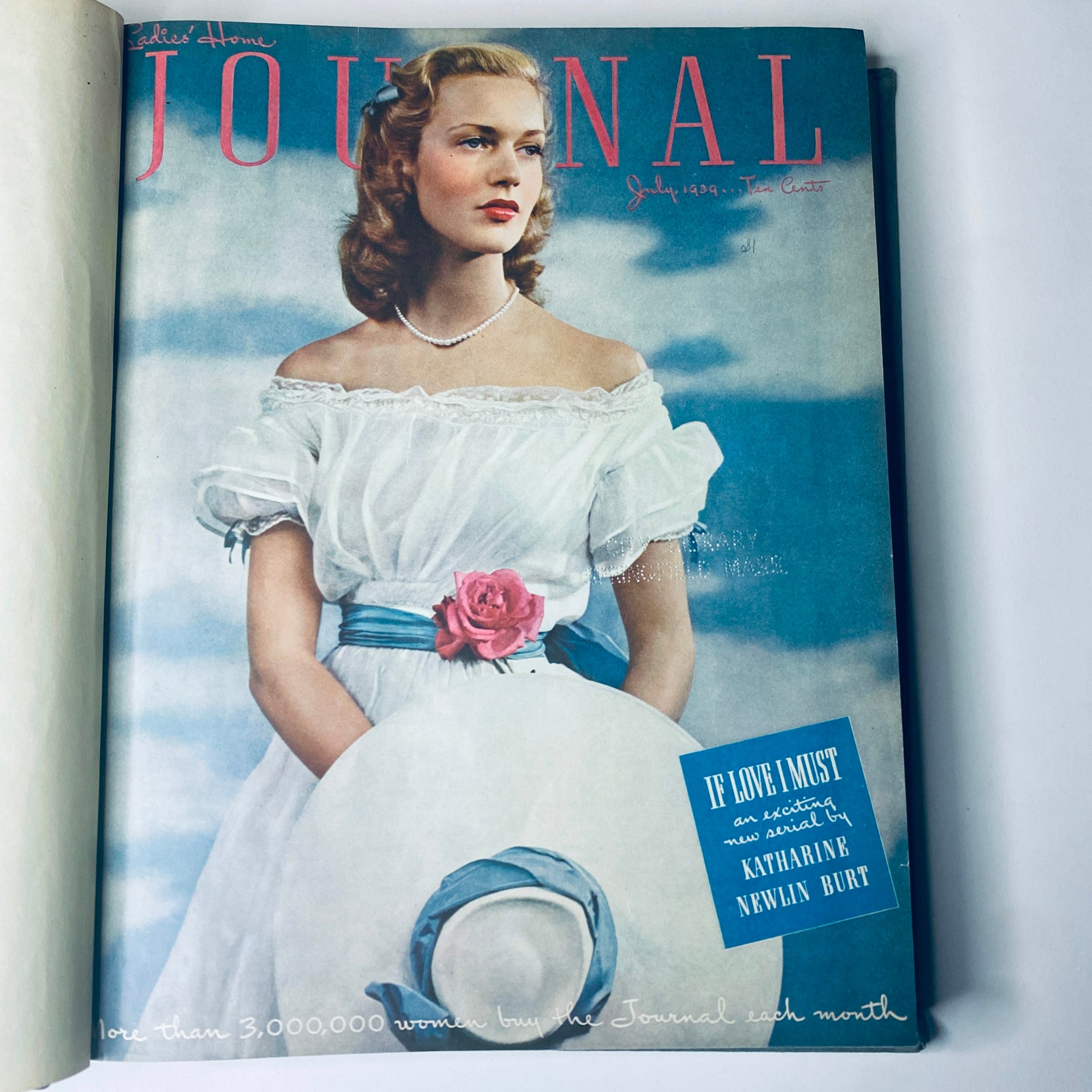 July 1939 edition cover of the Ladies' Home Journal, featuring a lady in a vintage dress with a large hat and a pink rose.