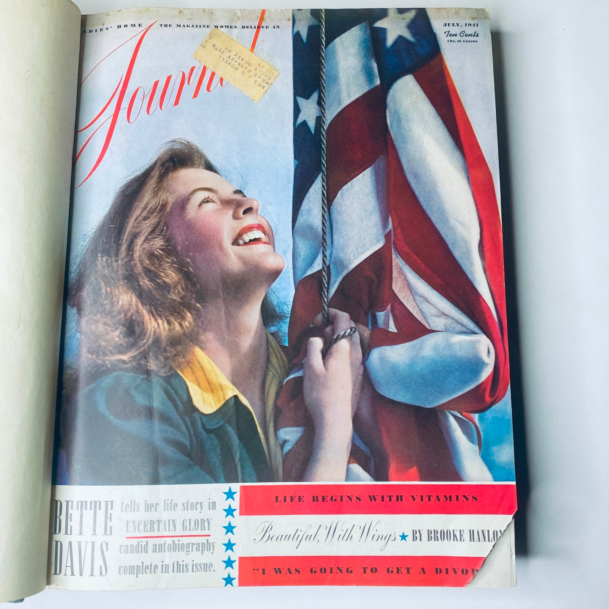 Cover of Ladies' Home Journal July 1941 featuring a woman smiling while holding an American flag. Part of the 1941 full year collection of the magazine.
