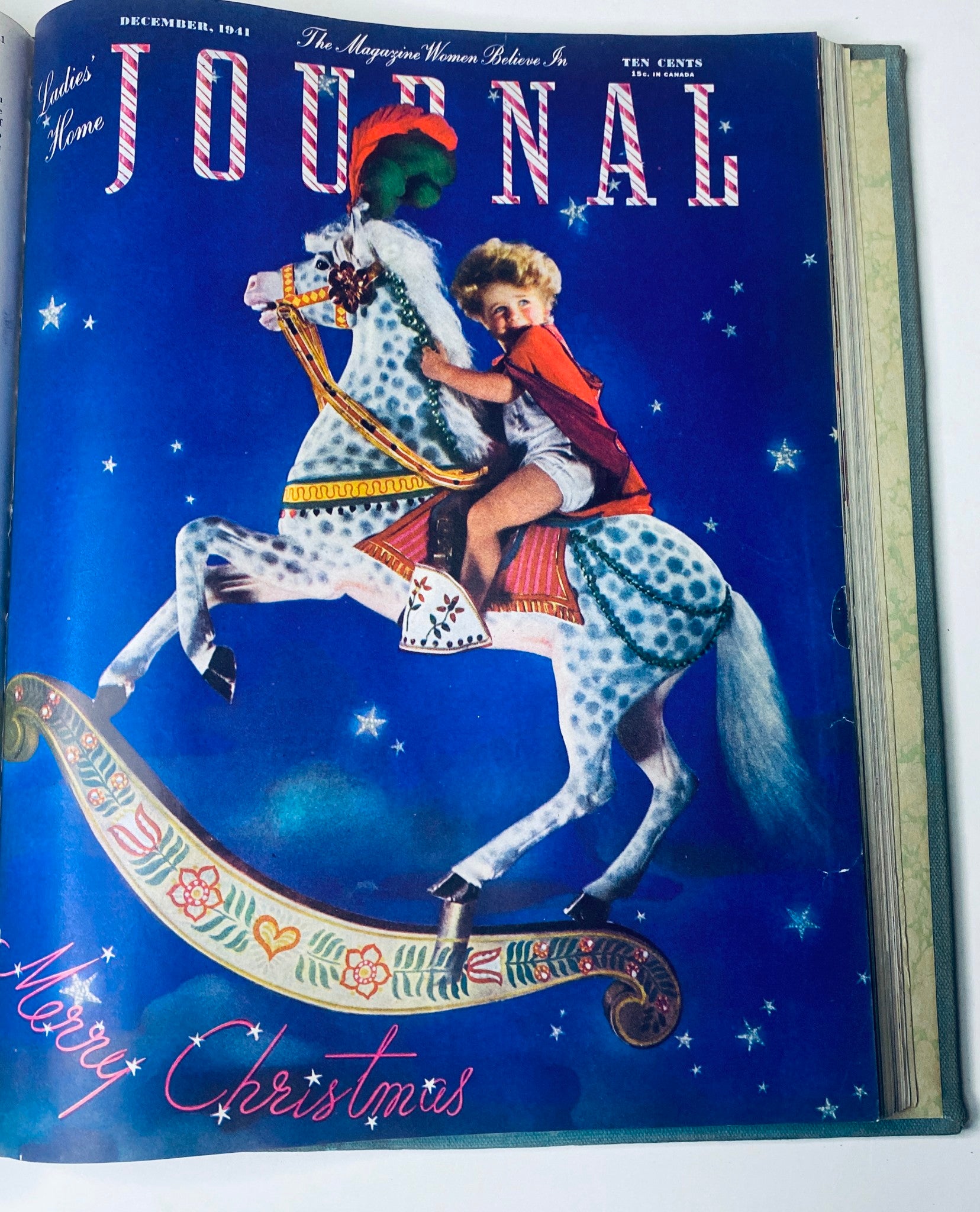 Colorful December 1941 cover of Ladies' Home Journal Bound Magazine 1941, featuring a child on a rocking horse against a blue festive background.