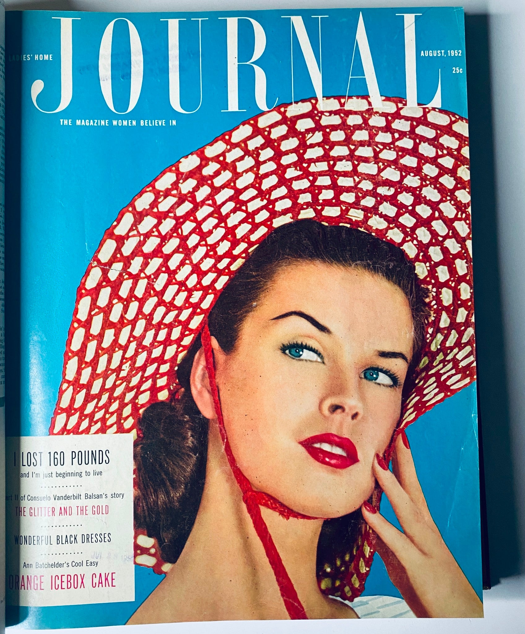 Cover of Ladies' Home Journal, August 1952, featuring a woman in a red hat, emphasizing beauty and elegance, with bold graphic design elements.