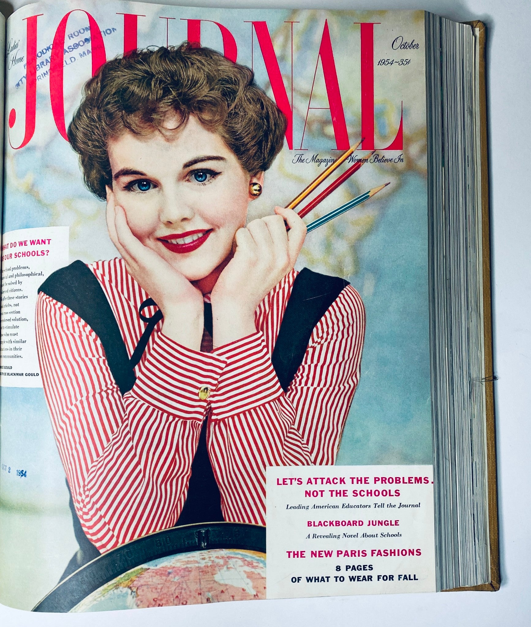 Cover image of the Ladies' Home Journal Bound Magazine for October 1954 showcasing a woman with a cheerful smile, adorned with a striped red shirt and holding colorful pencils. This issue discusses educational topics and fashion.