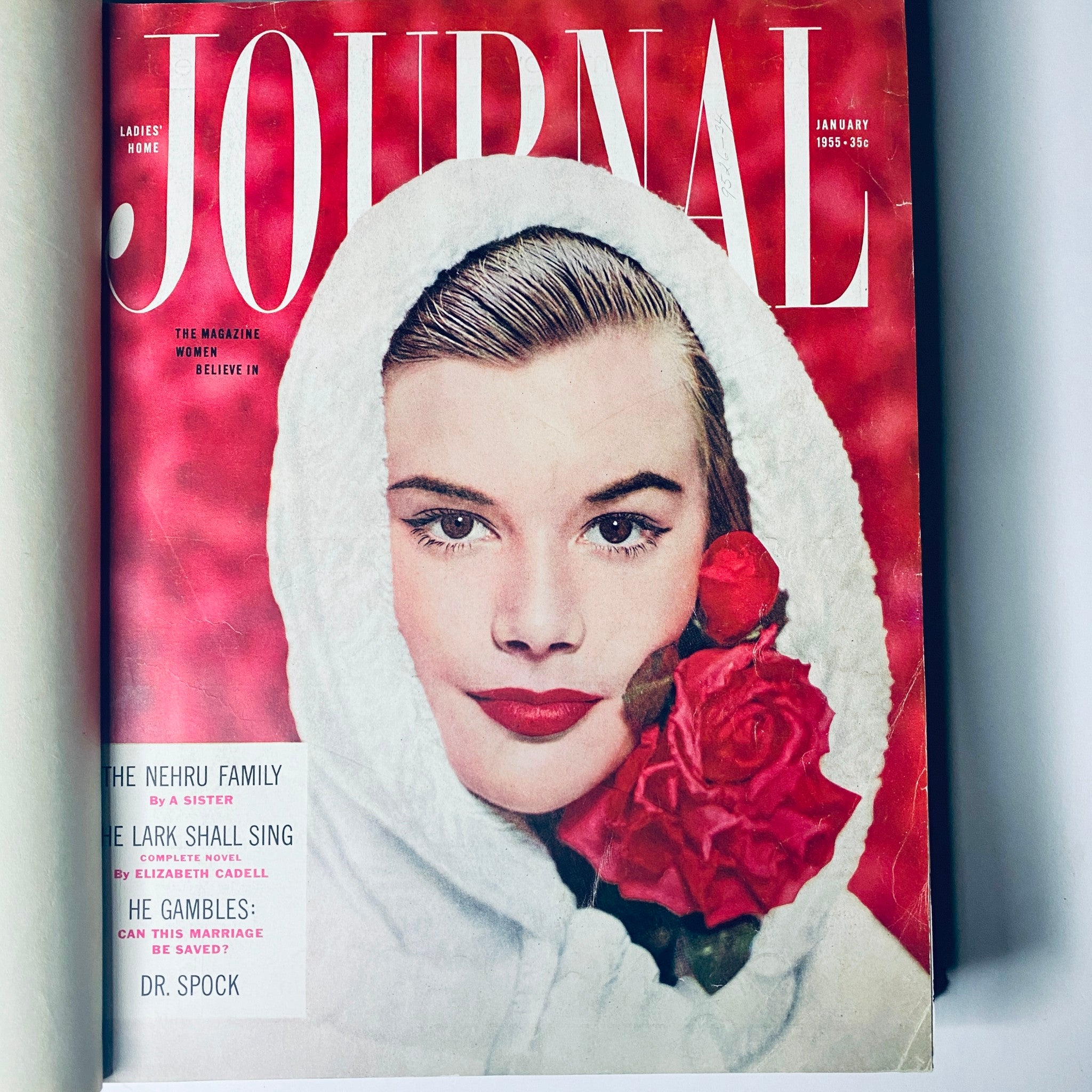 January 1955 cover of Ladies' Home Journal displaying a woman with red roses and a white hood, symbolizing mid-century fashion and beauty.