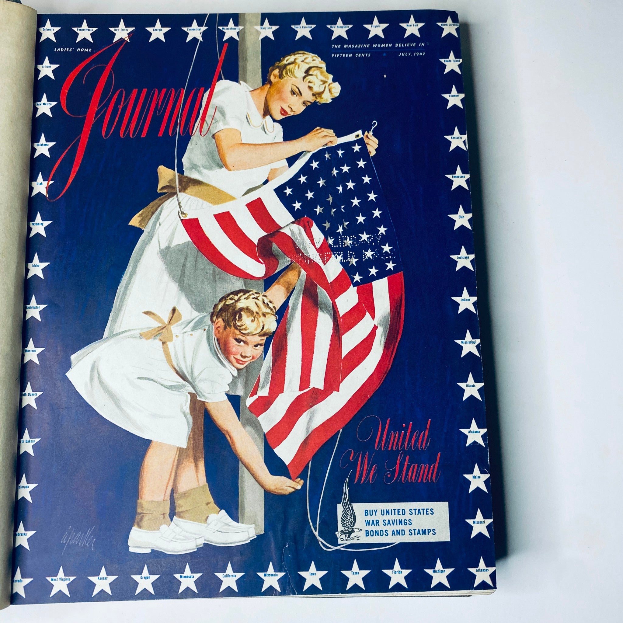 Cover of Ladies' Home Journal Library Bound Magazine 1942, featuring a woman and a child hanging an American flag, reflecting the patriotic spirit of the era during World War II.