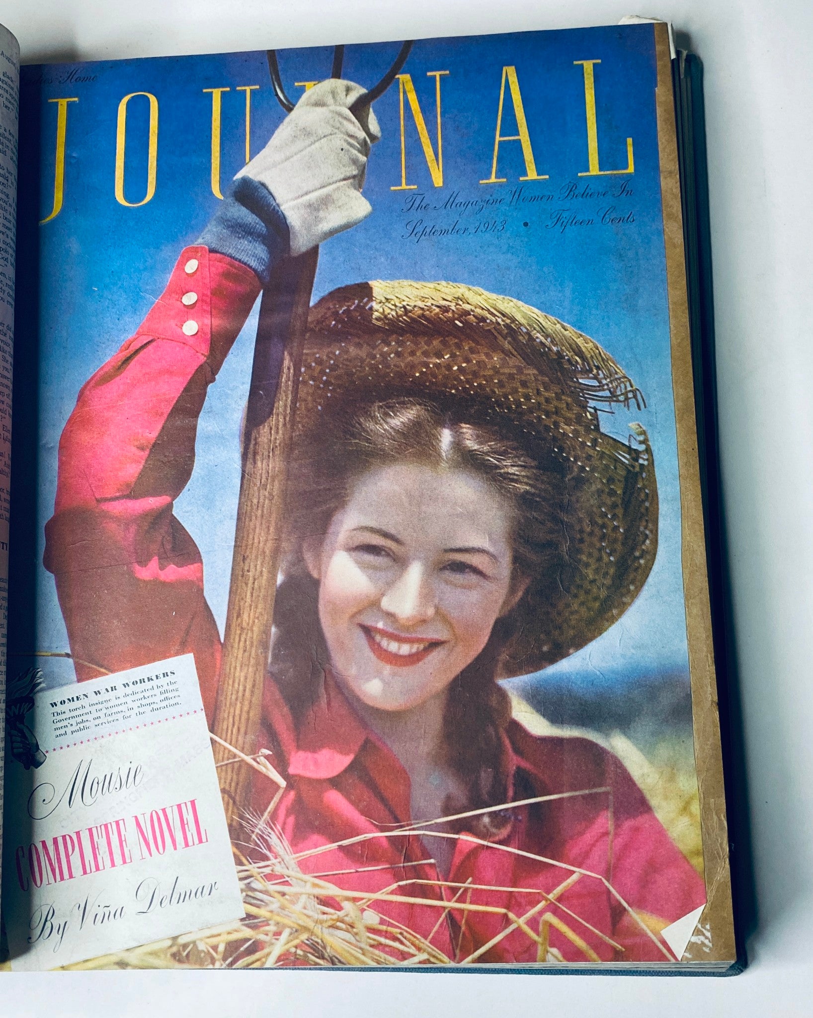 Cover of Ladies' Home Journal, September 1943 edition, featuring a woman in a straw hat with a scythe, advertising 'Mousie' complete novel by Vina Delmar.