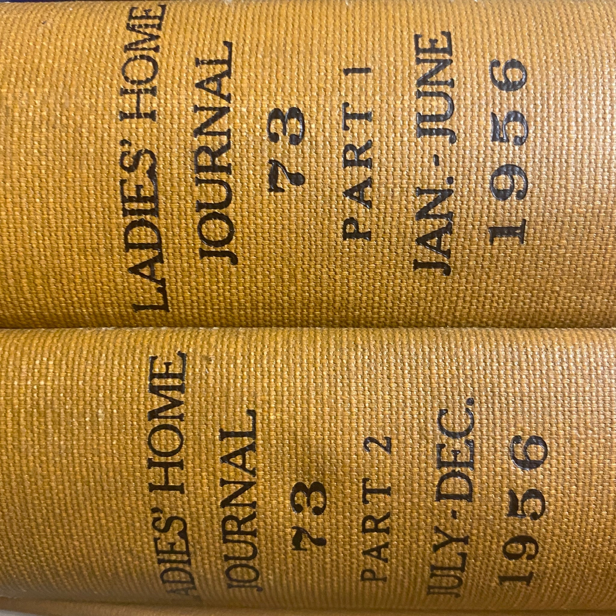 Ladies' Home Journal Library Bound Magazine 1956 Full Year January - December, a close-up of the spines of two bound volumes displaying 'Ladies Home Journal' title, part numbers, and publication dates.